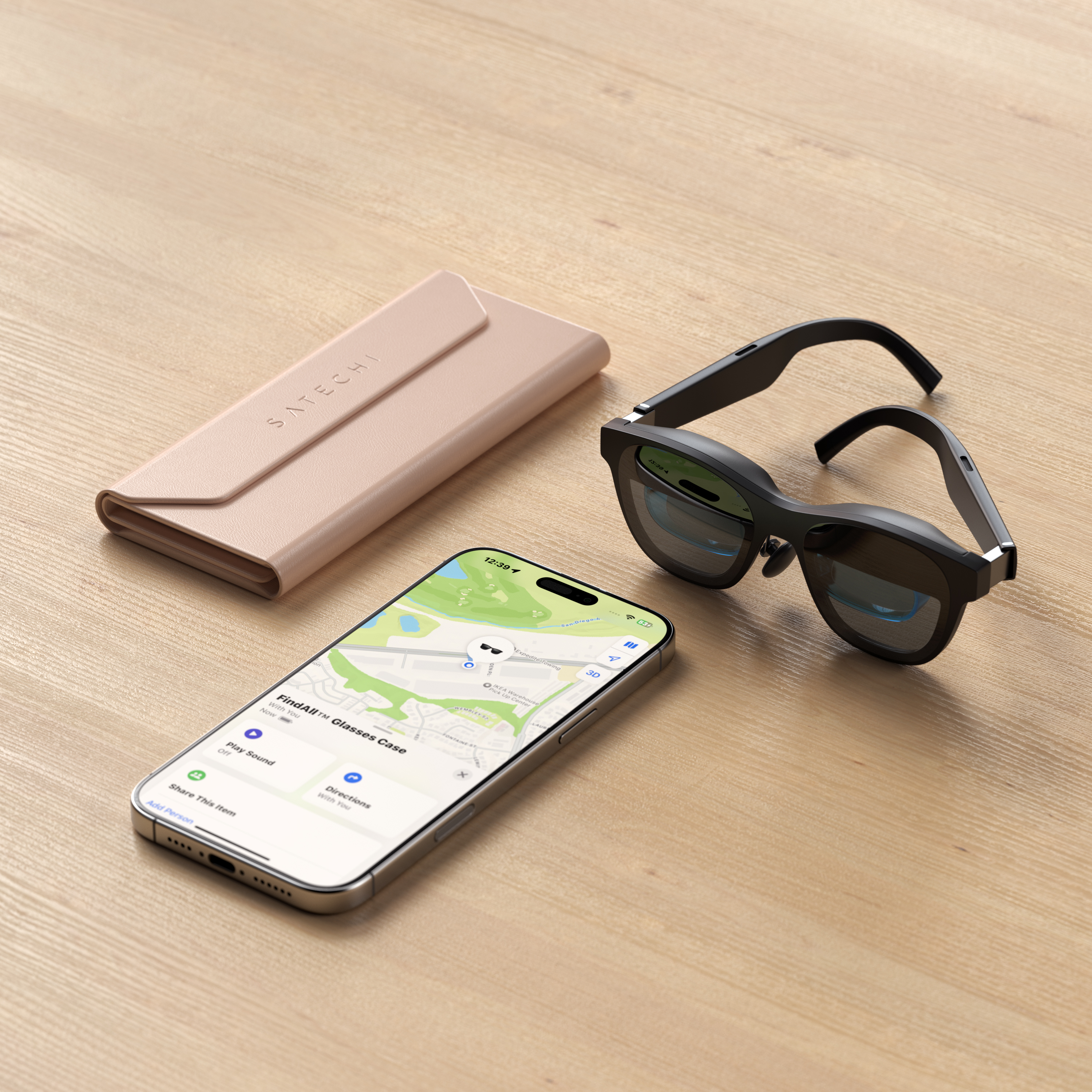 Una custodia Satechi rosa, occhiali neri e un iPhone con mappa su tavolo di legno.
