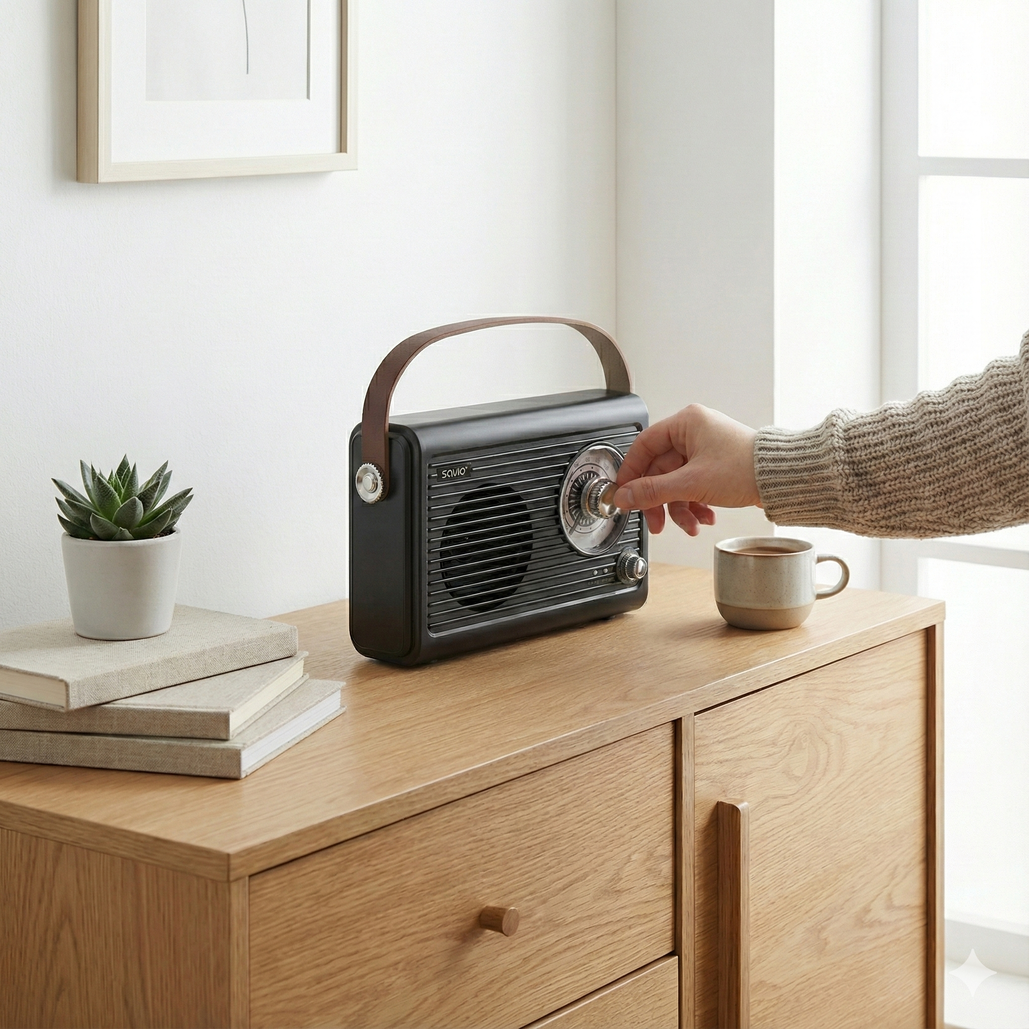 Ręka kręci czarnym radiem retro na drewnianej komodzie obok filiżanki kawy.