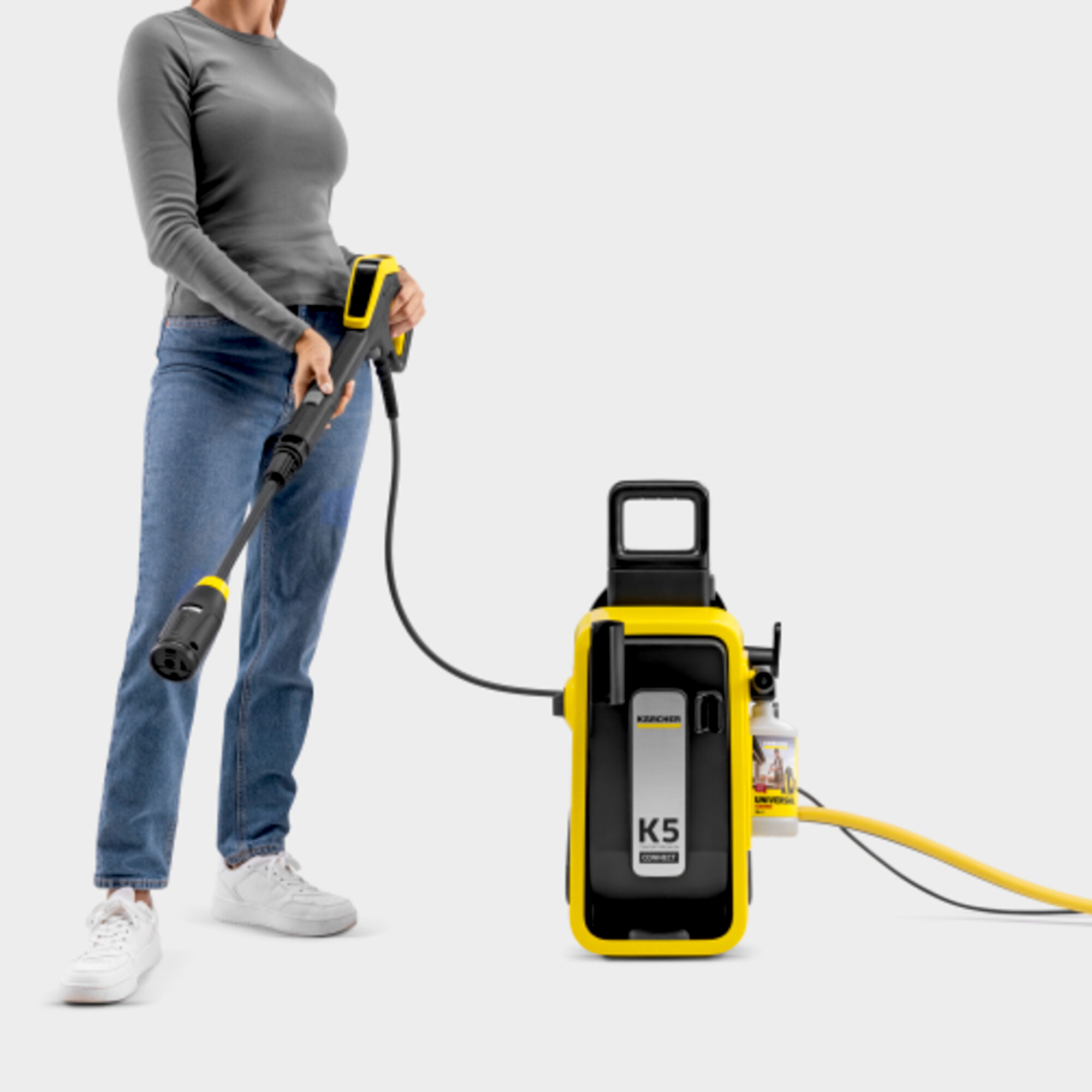 Osoba trzymająca myjkę ciśnieniową i żółtą jednostkę.