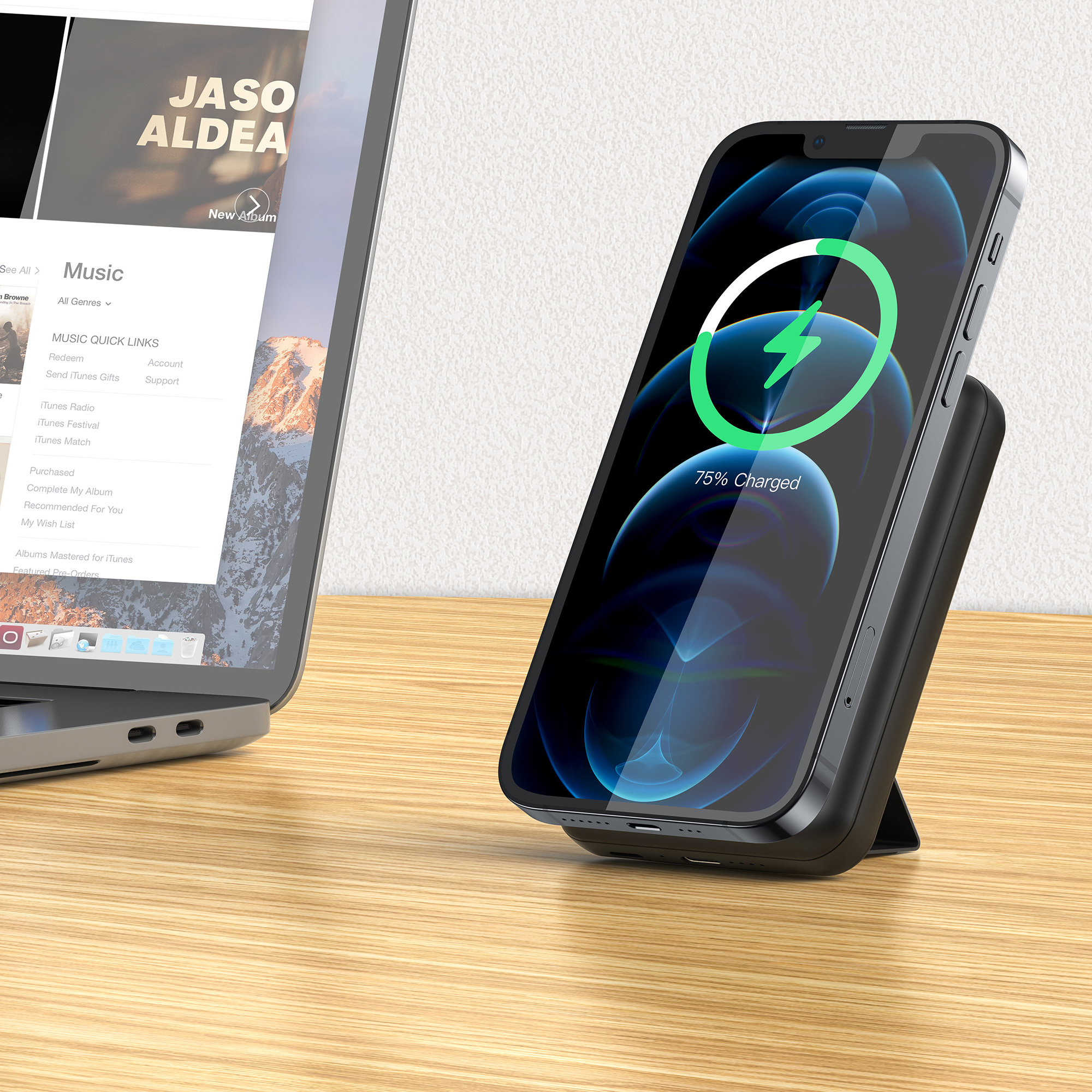 Ein Smartphone lädt auf einem Ständer neben einem Laptop mit Musik-App.