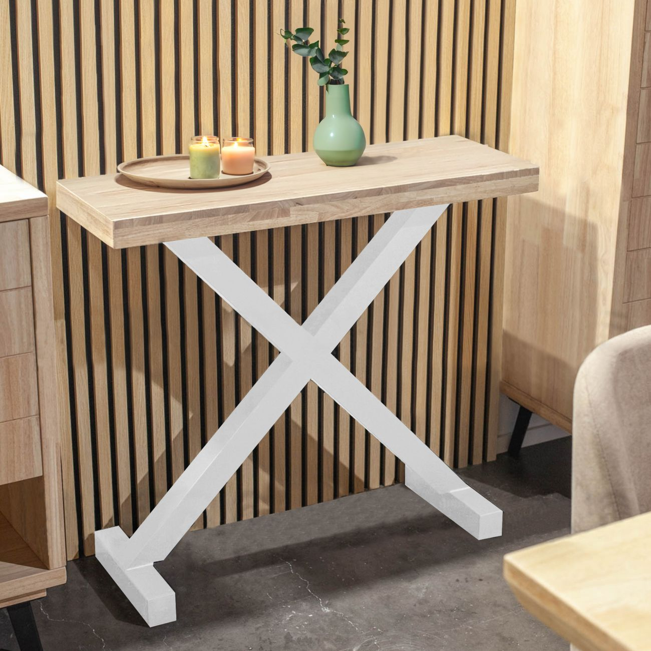 Mesa de madera estrecha con base en X blanca, decorada con velas y jarrón.