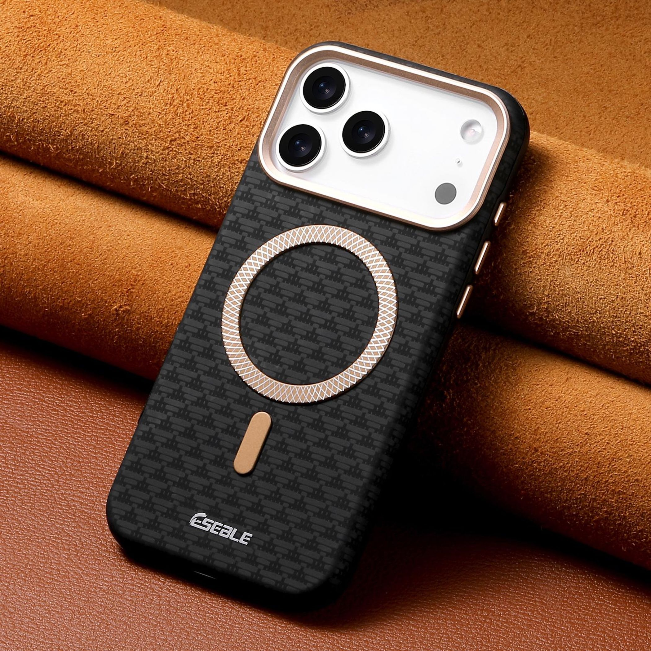 Funda negra para teléfono con tres cámaras y anillo dorado sobre cuero marrón.