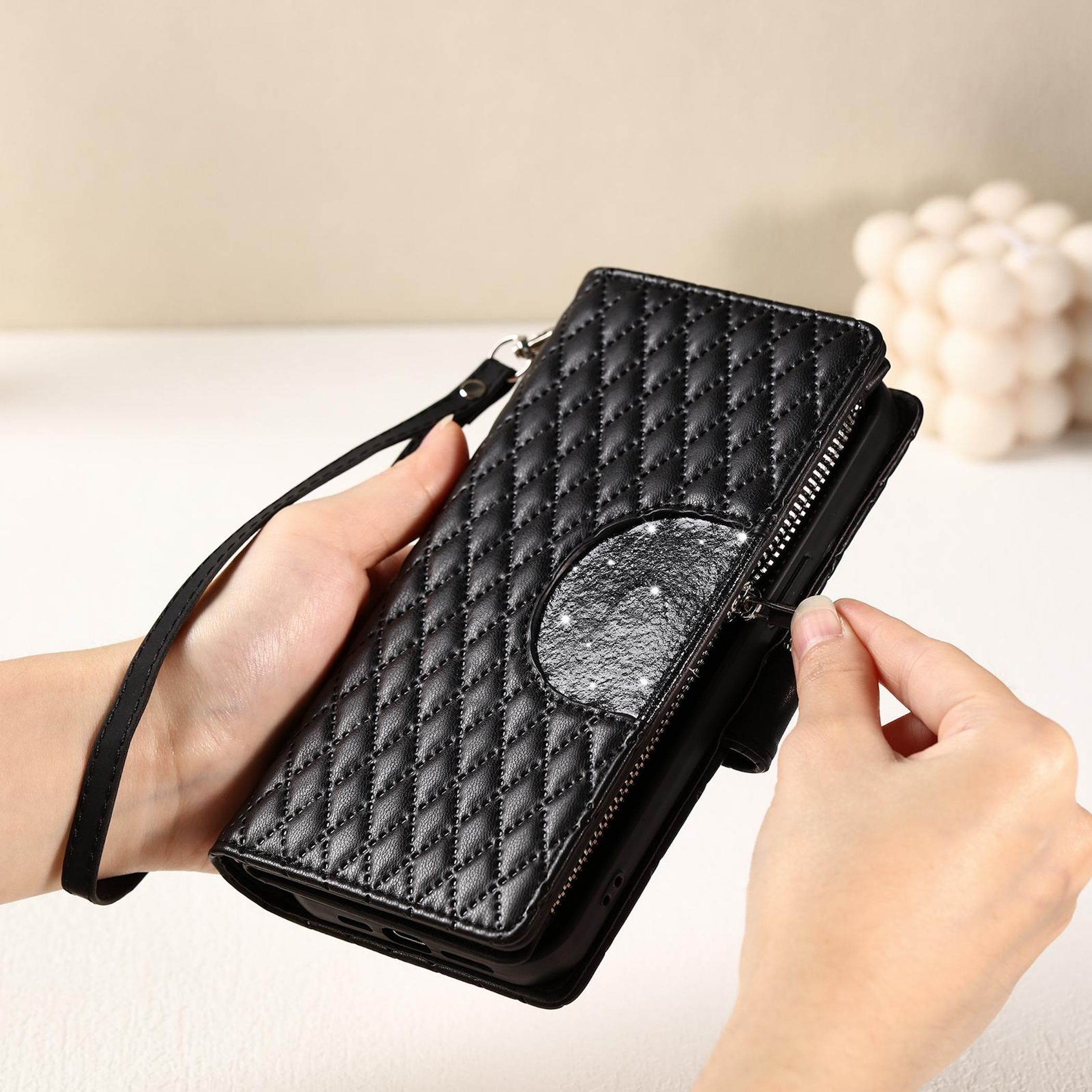Schwarze gesteppte Brieftasche mit Reißverschluss und einem glitzernden Ausschnitt.
