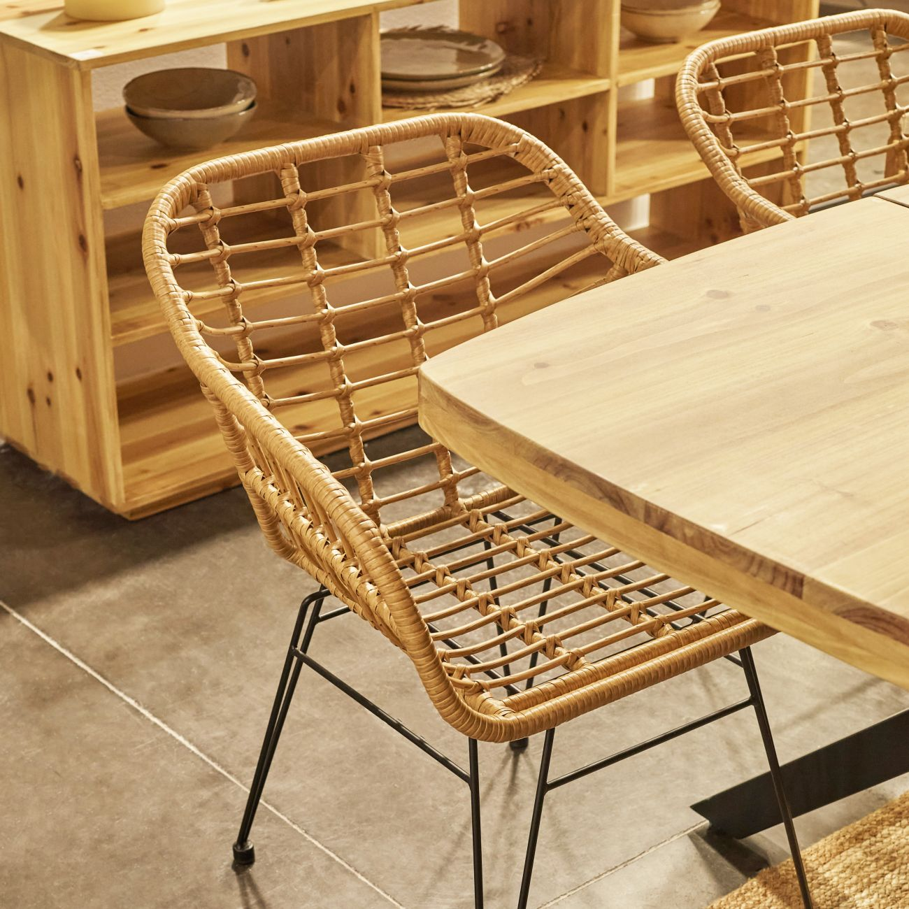 Una mesa de comedor de madera con sillas de ratán y patas de metal negro.