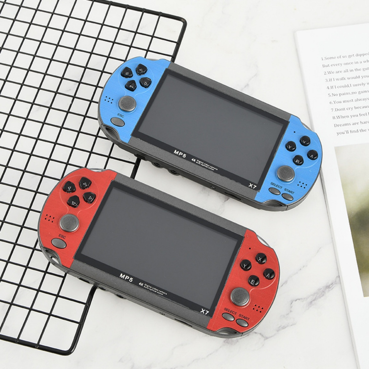 Zwei Handheld-Spielekonsolen, blau und rot, liegen nebeneinander auf einem Gitter.