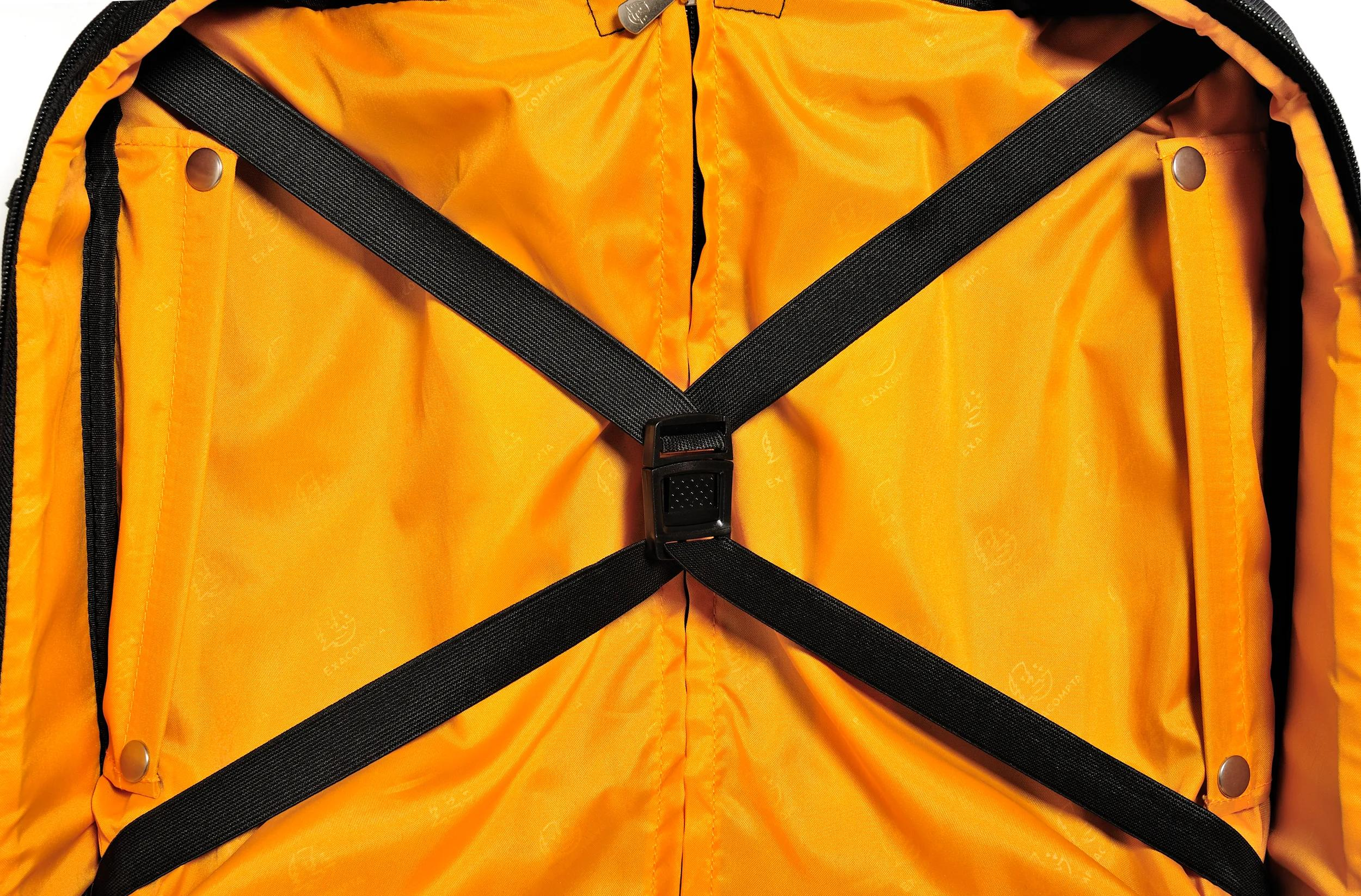 El interior de una maleta con forro naranja y correas negras.