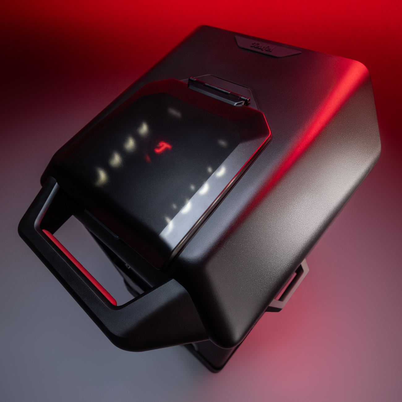 Dispositivo nero e angolare con manici e illuminazione rossa.