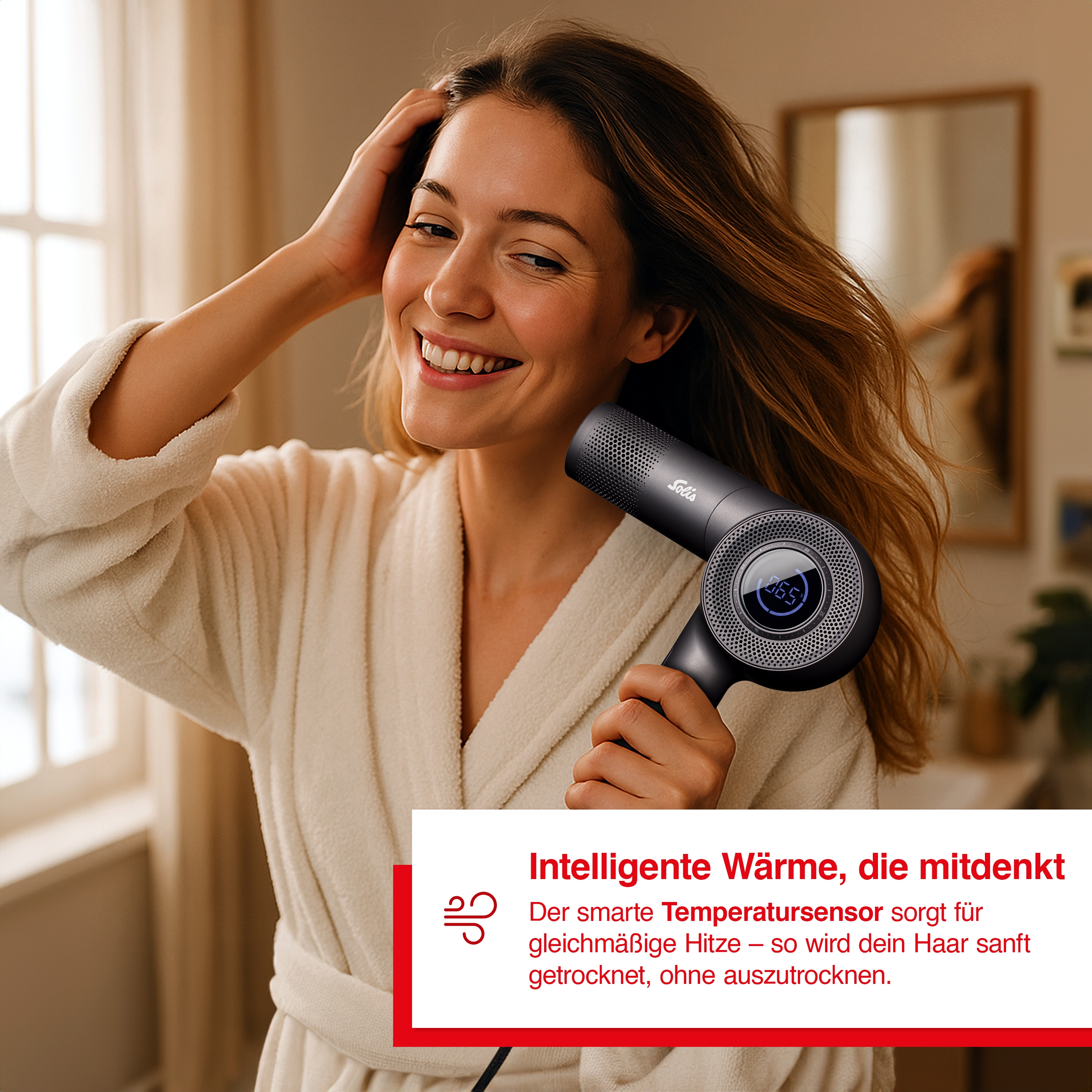 Eine Frau in einem Bademantel hält einen schwarzen Haartrockner mit digitaler Anzeige.
