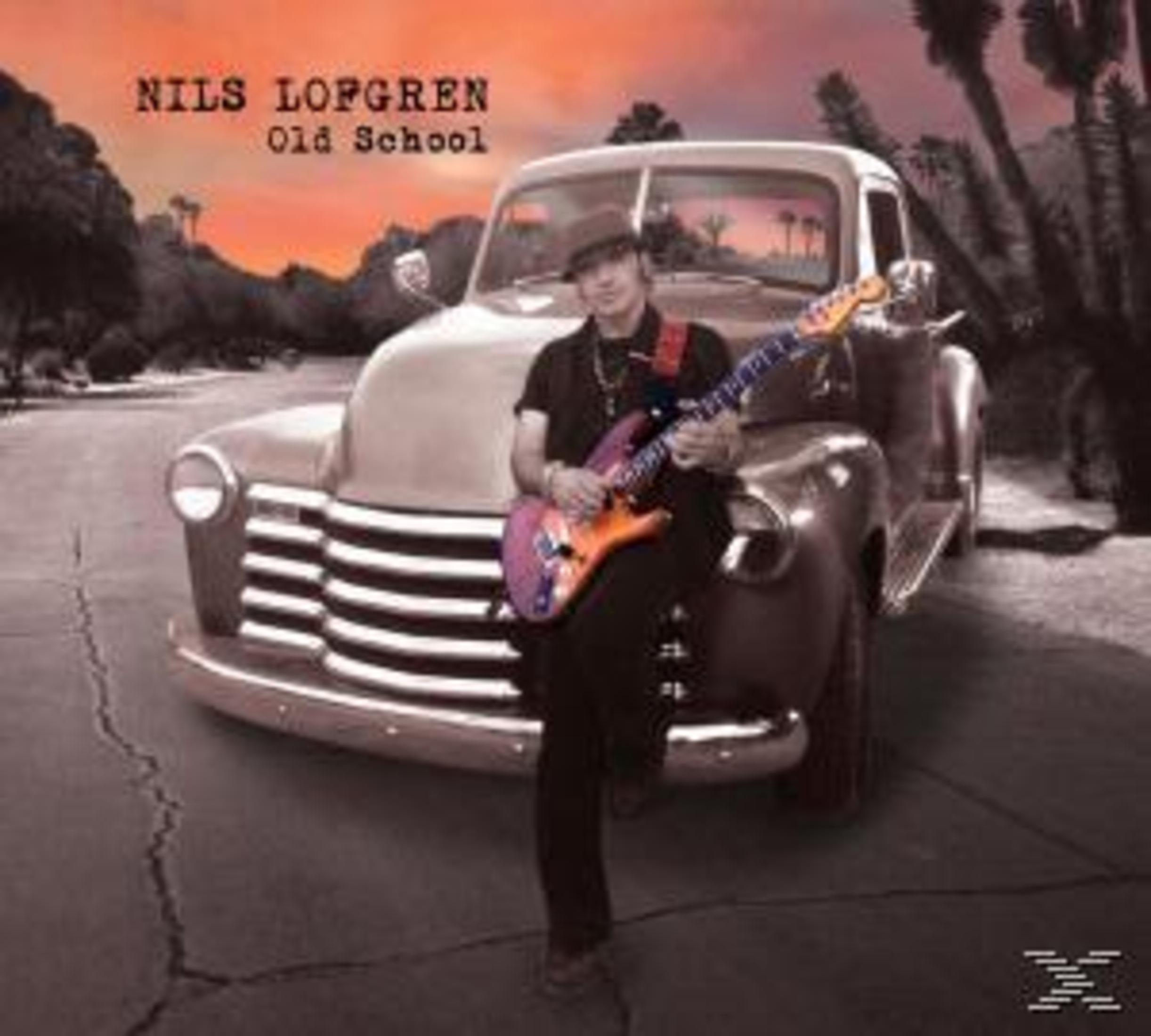 Ein Mann mit Hut spielt Gitarre vor einem Oldtimer-Truck bei Sonnenuntergang.