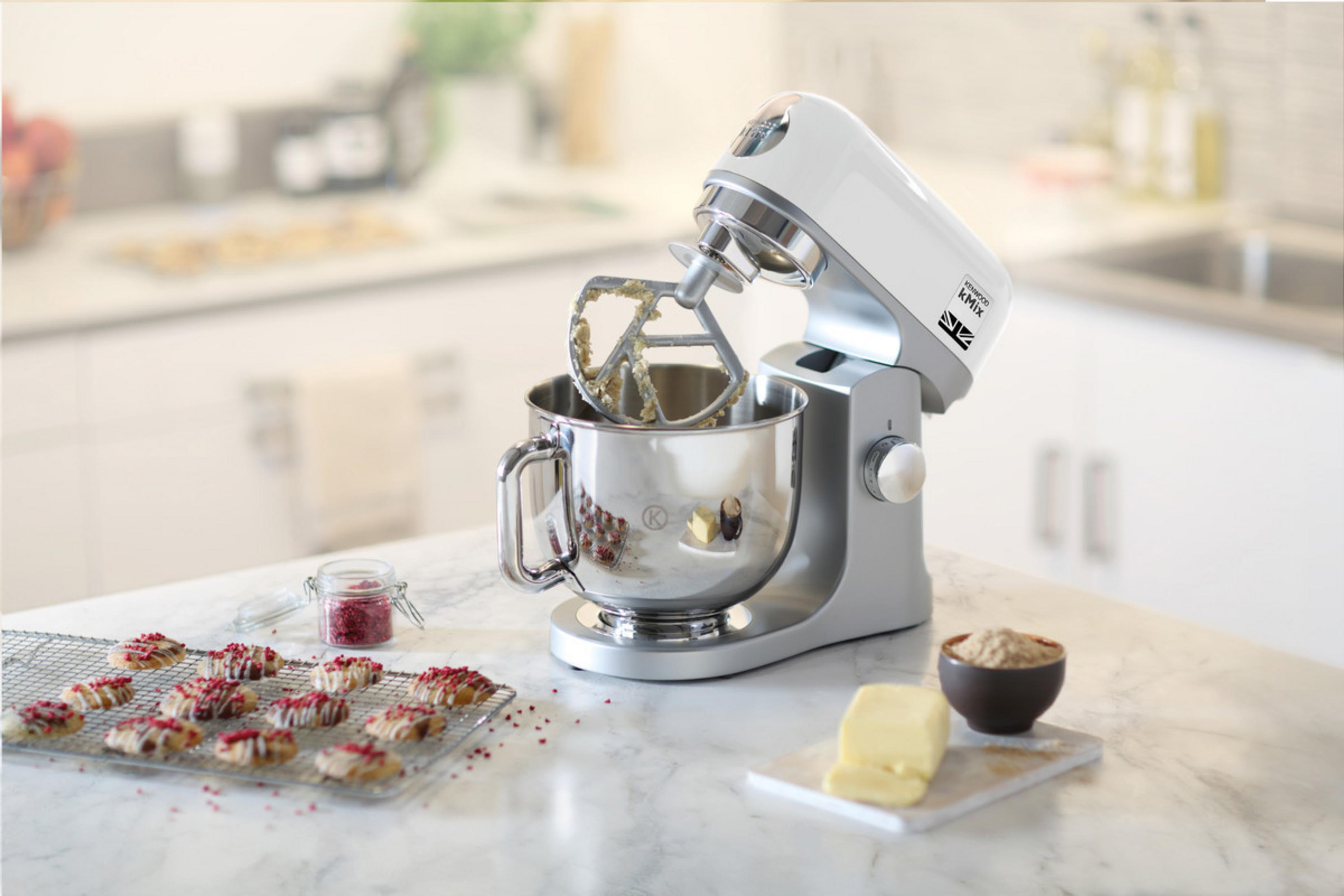 Ein weißer Küchenmixer steht auf einer Marmorarbeitsplatte mit Keksen und Zutaten.