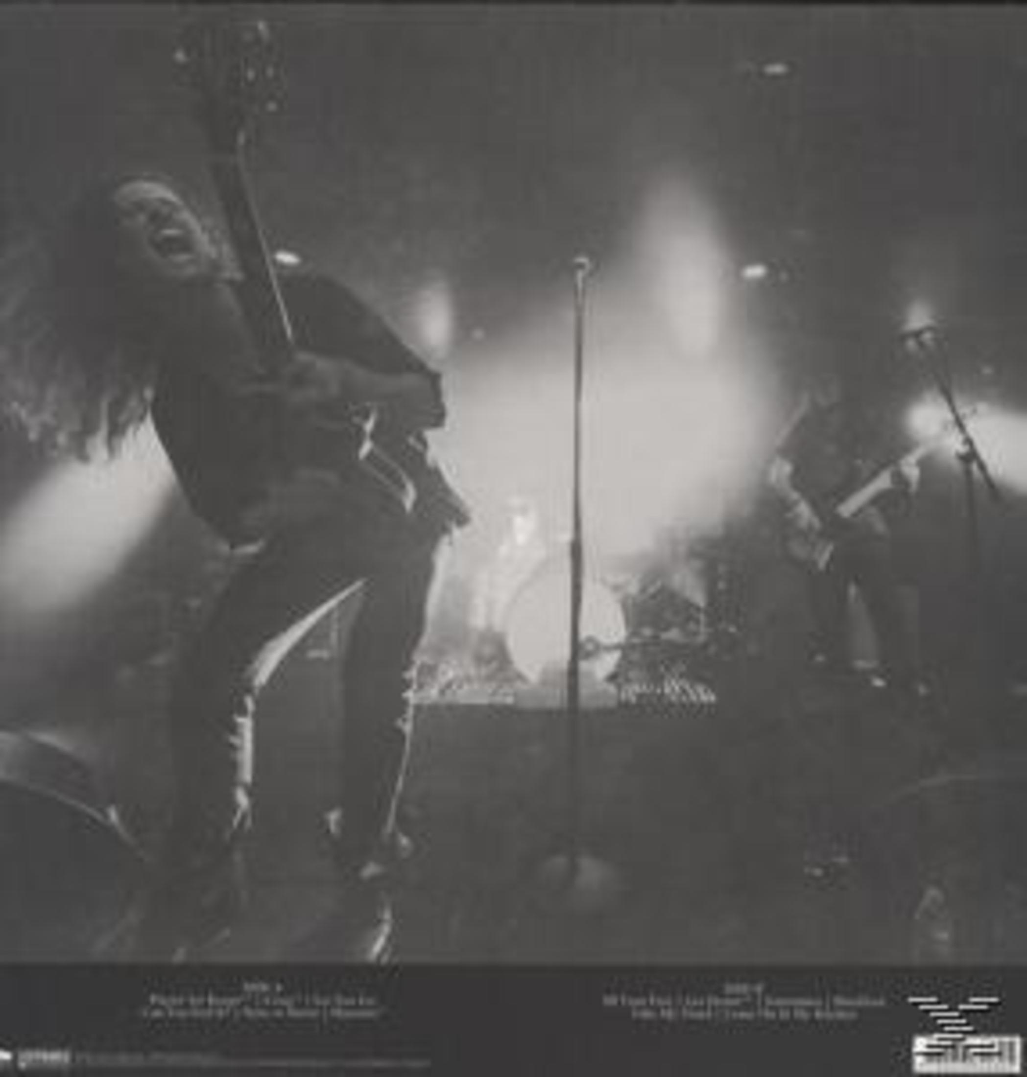 Schwarz-Weiß-Foto einer Band auf der Bühne mit Scheinwerfern.