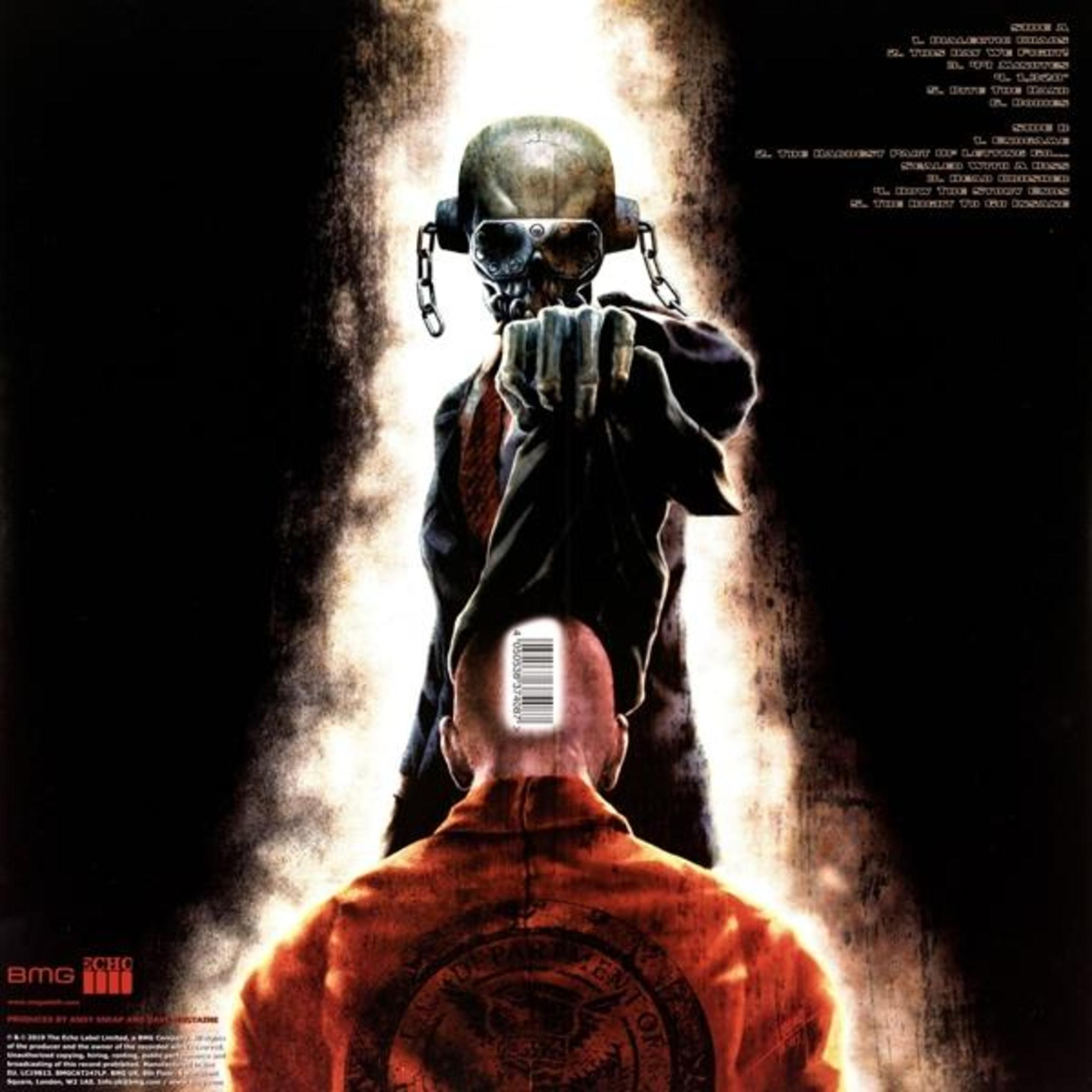 Ein Totenkopf mit Brille und Kopfhörern hält ein Hemd vor einem Mann in orangefarbener Kleidung.