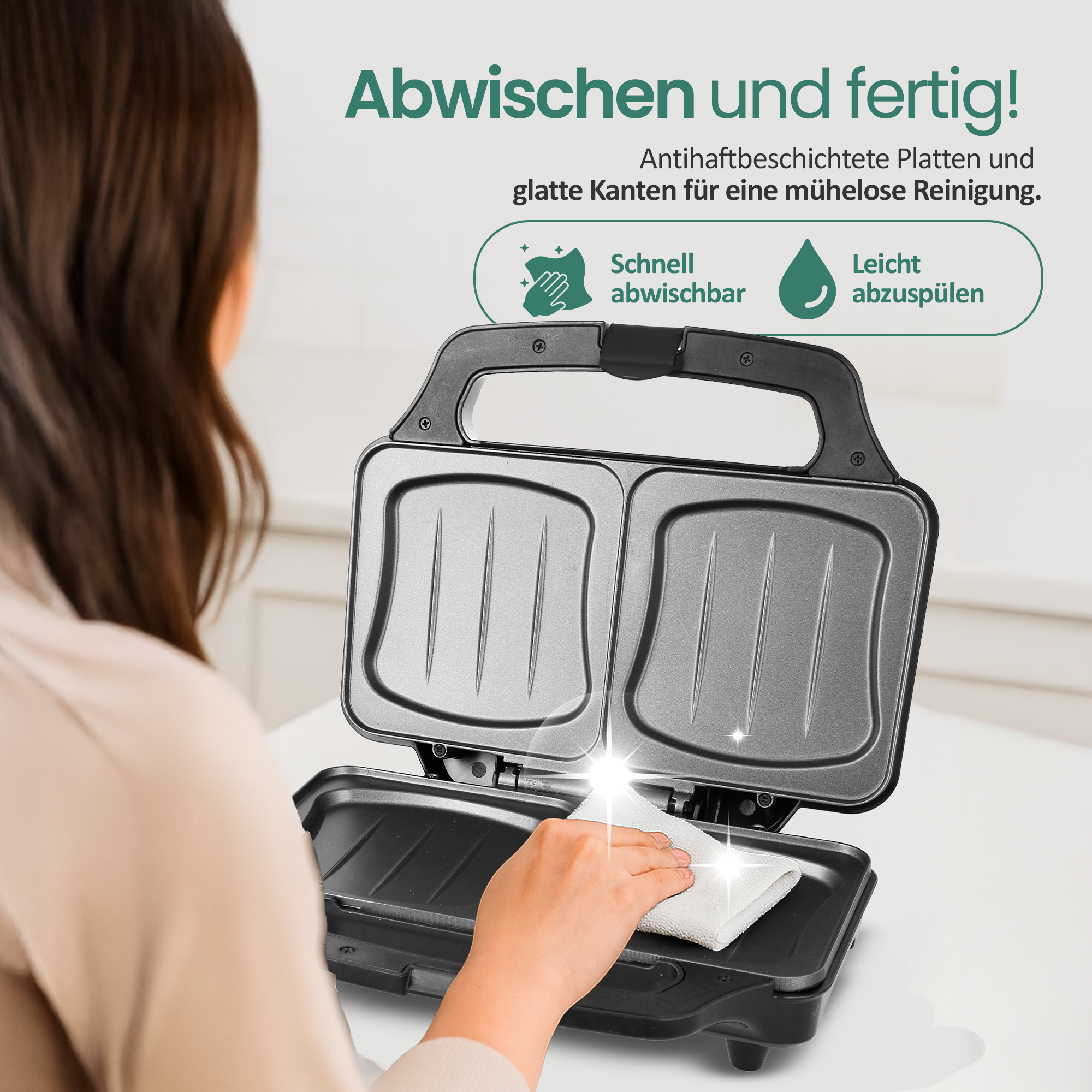 Eine Person wischt eine Sandwichpresse mit einem Tuch ab.
