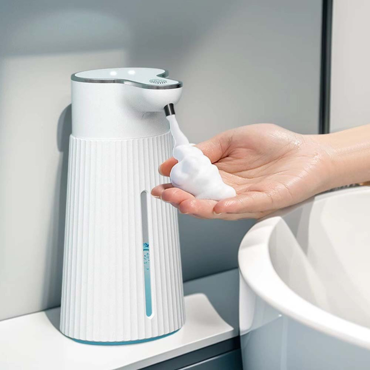 Ein weißer Schaumseifenspender gibt Schaum in eine Hand, daneben ein Waschbecken.