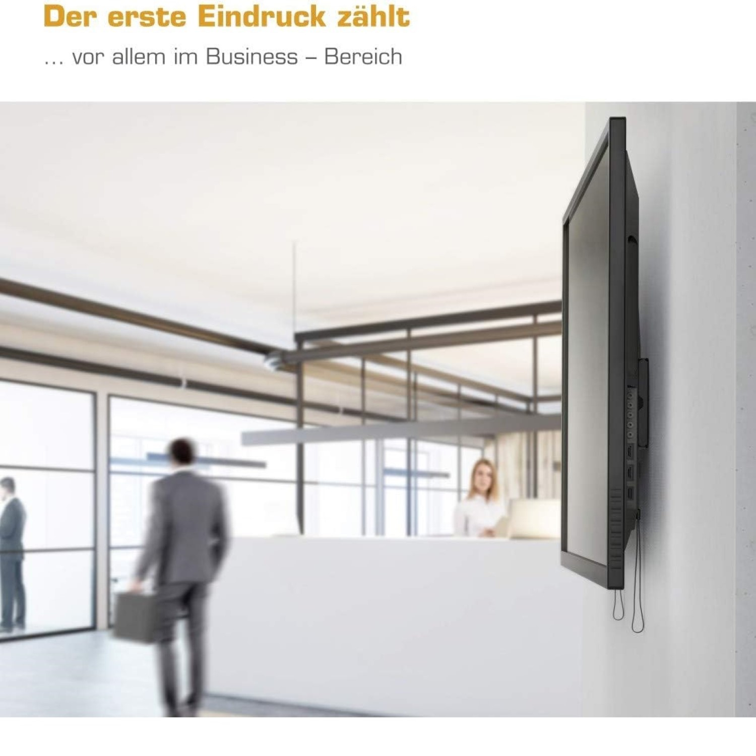 Ein Mann mit Koffer in einem modernen Büro, ein Bildschirm hängt an der Wand.