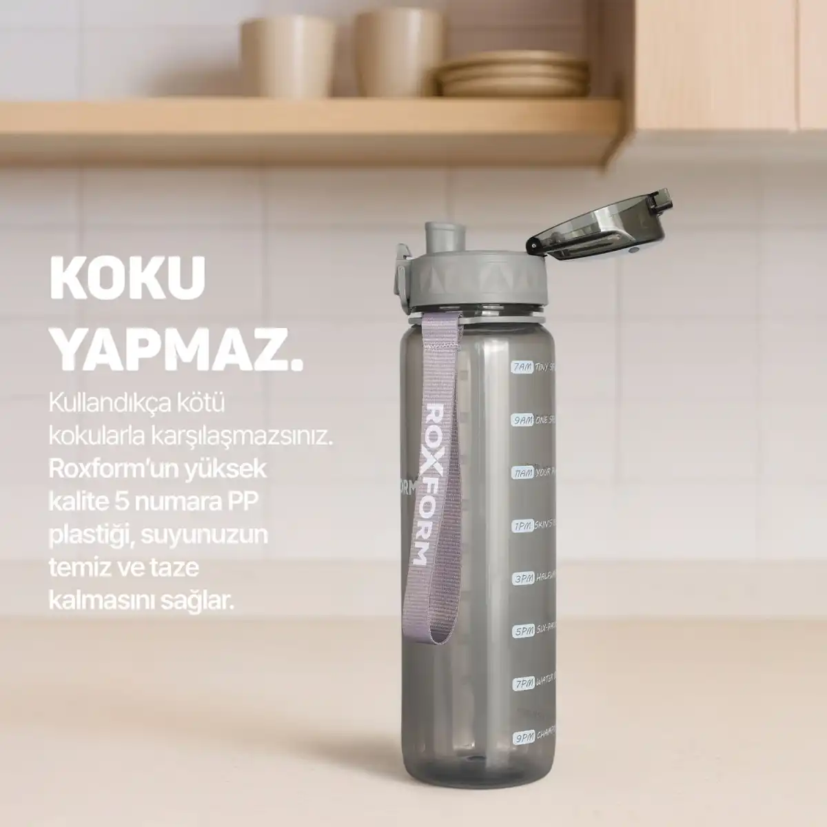 Zaman işaretleri ve askısı olan gri su şişesi tezgahın üzerinde duruyor.