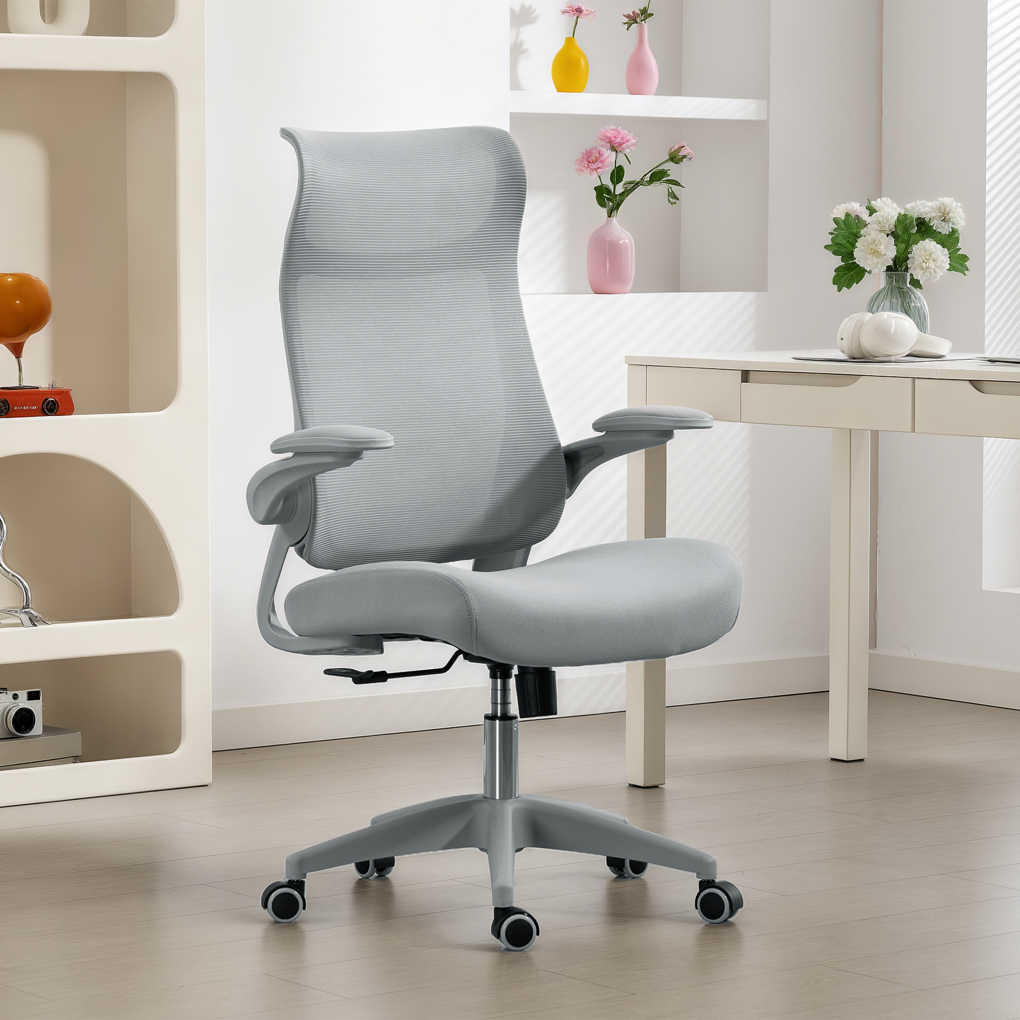 Silla de oficina gris con respaldo de malla frente a un escritorio con decoración.