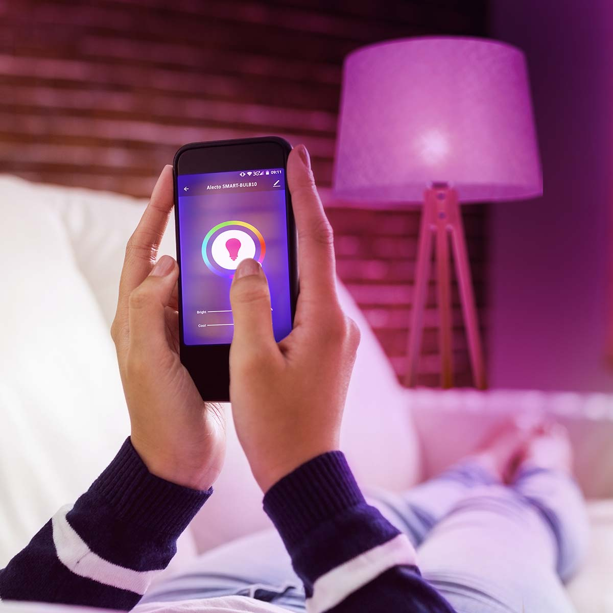 Osoba steruje inteligentną lampą przez aplikację na smartfonie. Różowe światło.