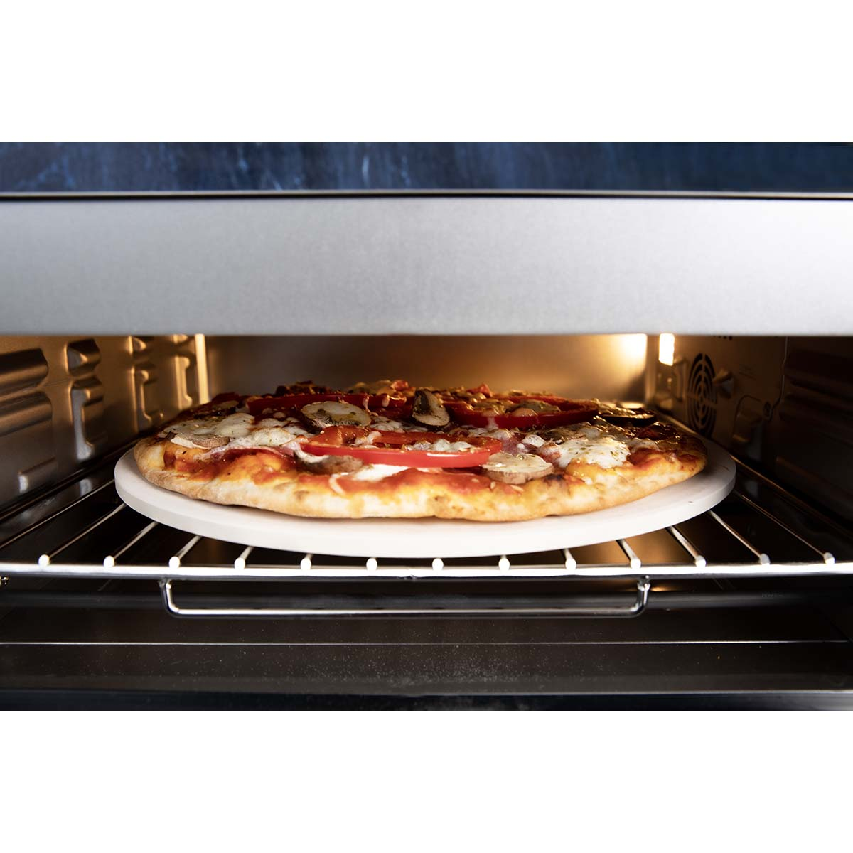 Pizza z pomidorami i grzybami piecze się w piekarniku na kamieniu do pizzy.