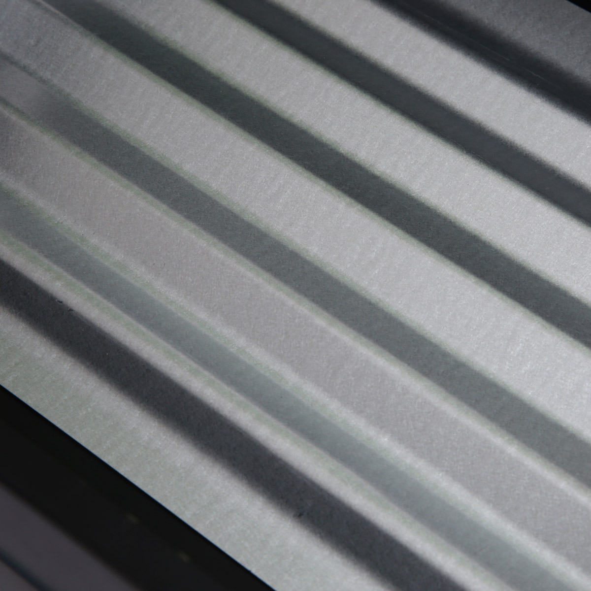 Zbliżenie szarej, prążkowanej powierzchni z ukośnymi cieniami.