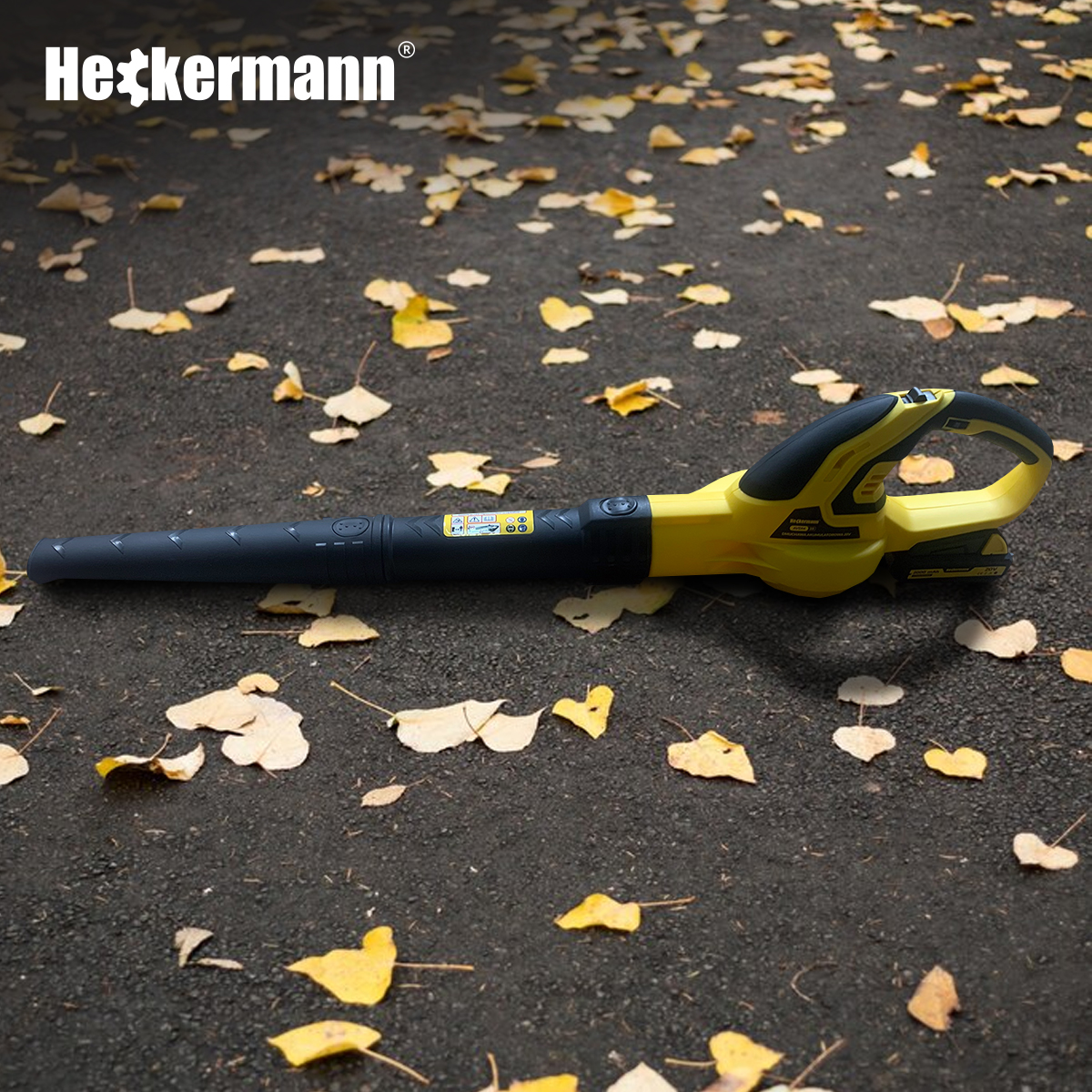 Żółto-czarna dmuchawa do liści leży na ścieżce pokrytej jesiennymi liśćmi.