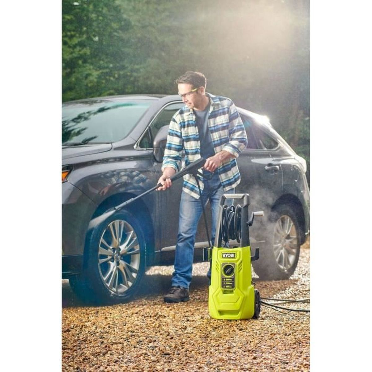 Man spuit donkere SUV schoon op grind oprit met hogedrukreiniger.