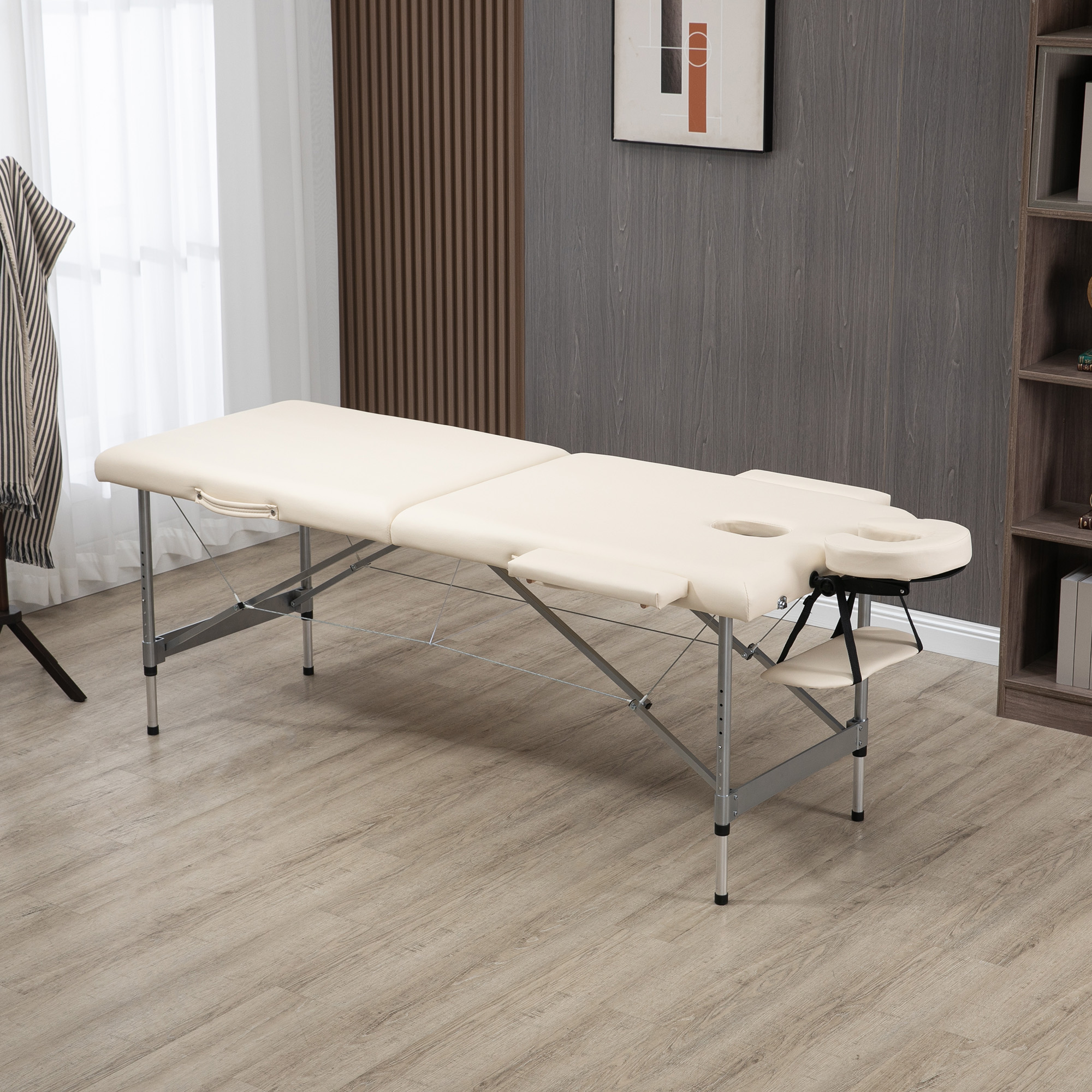 Una camilla de masajes beige claro con reposacabezas está en suelo de madera.