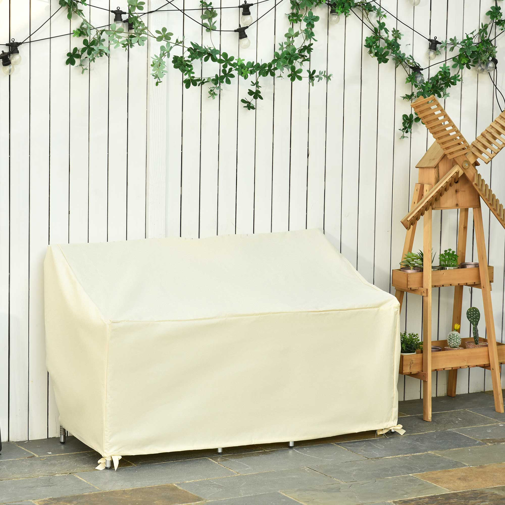 Una funda de sofá color crema frente a una pared de madera blanca con luces y enredaderas.