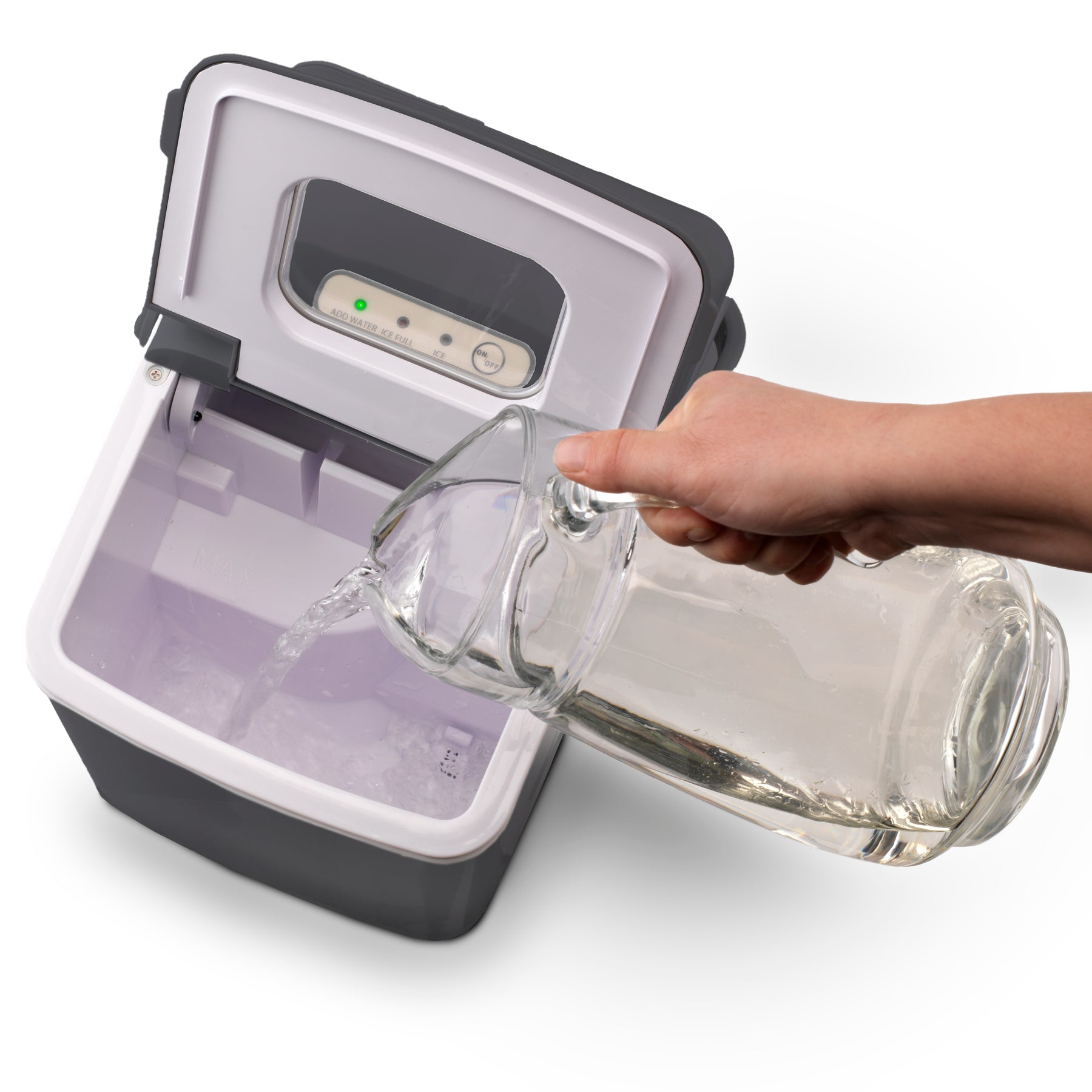 Eine Hand gießt Wasser aus einer Glaskaraffe in einen Eisbereiter.