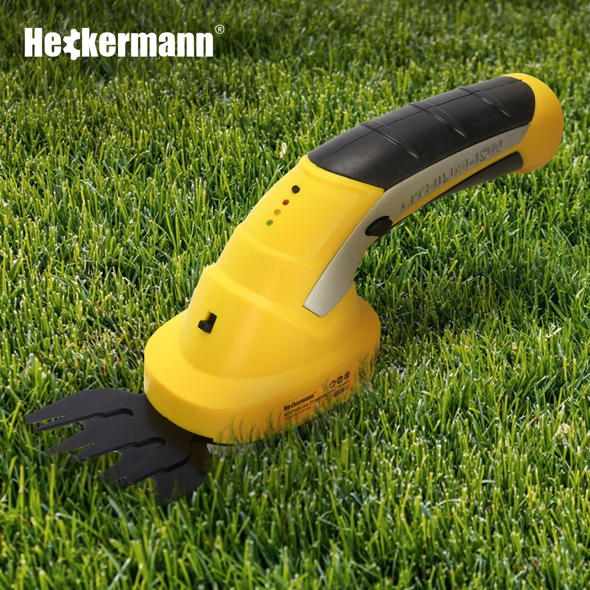 Żółta przycinarka Heckermann leży na zielonej trawie z nazwą marki nad narzędziem.