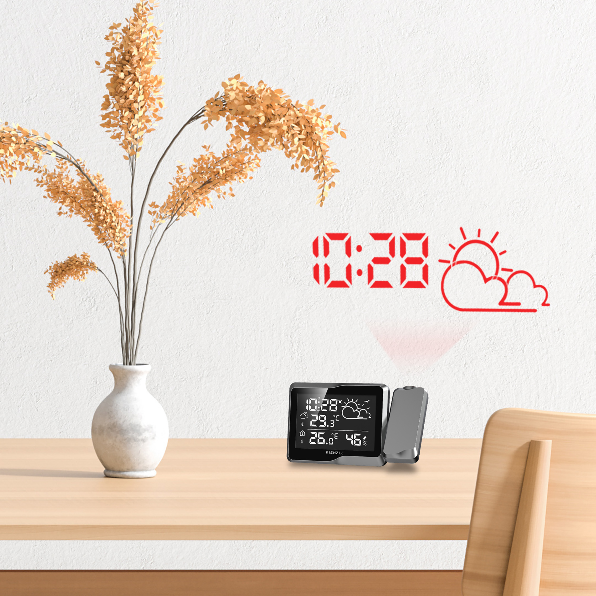 Un expositor meteorológico digital se sienta sobre una mesa de madera junto a un jarrón de flores secas.