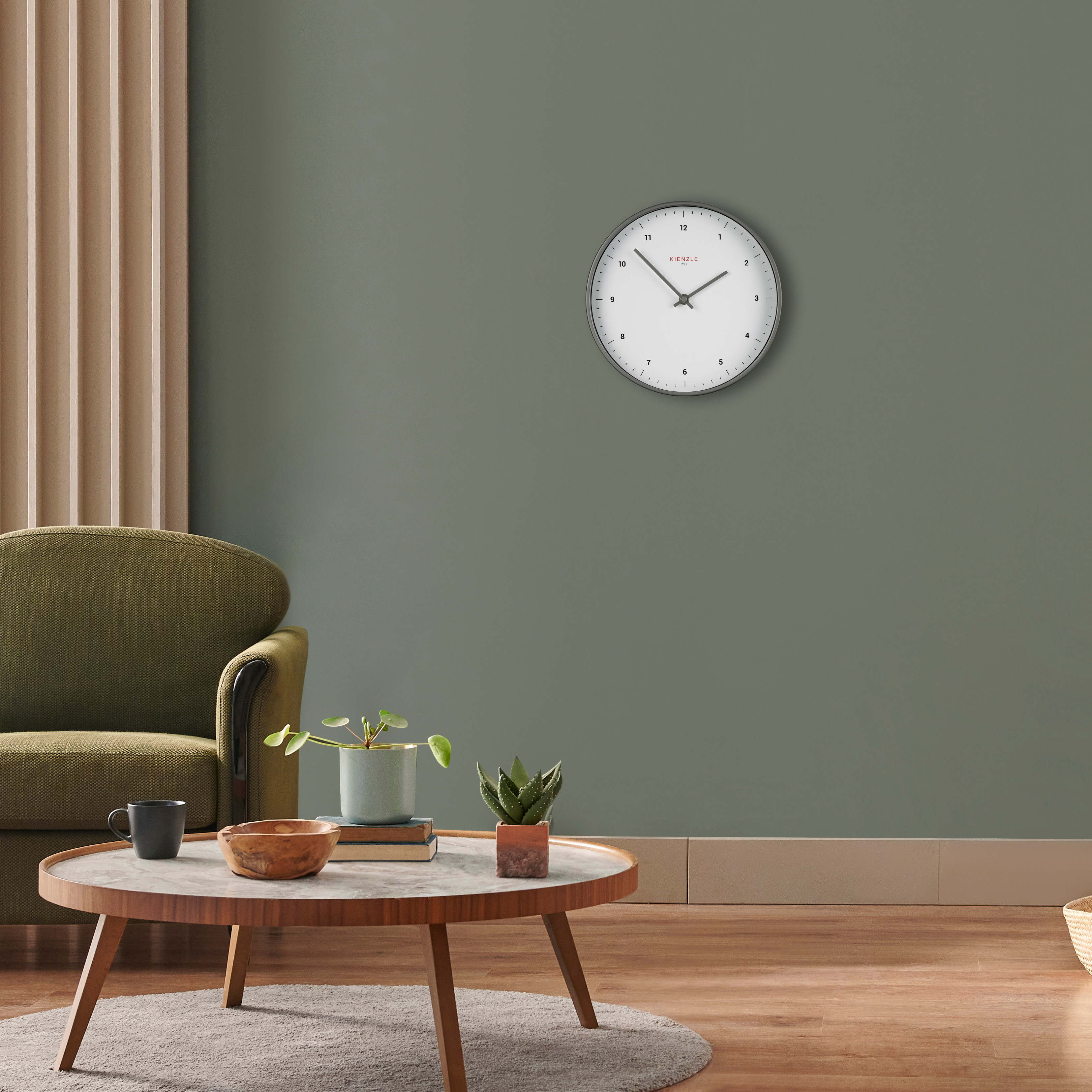 Una poltrona verde, un tavolino rotondo in legno con piante e un orologio da parete.