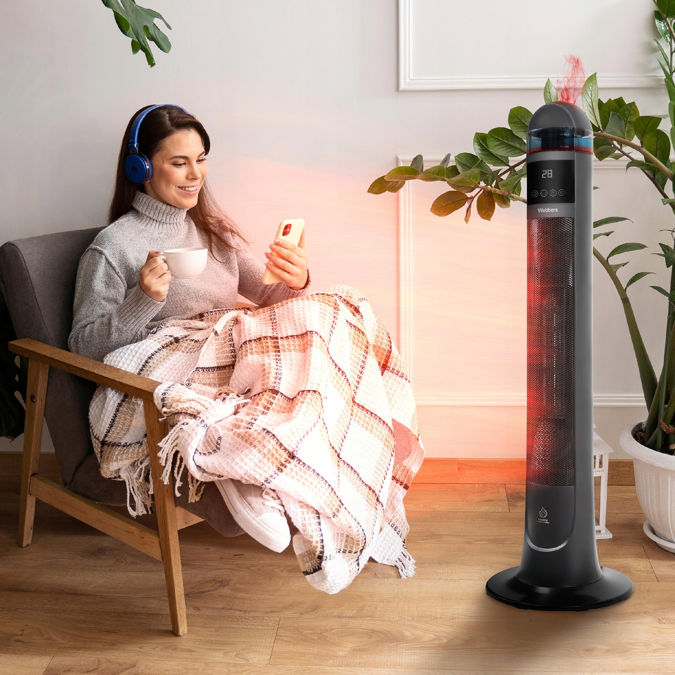 Kobieta w słuchawkach siedzi w fotelu, pije kawę i używa telefonu.