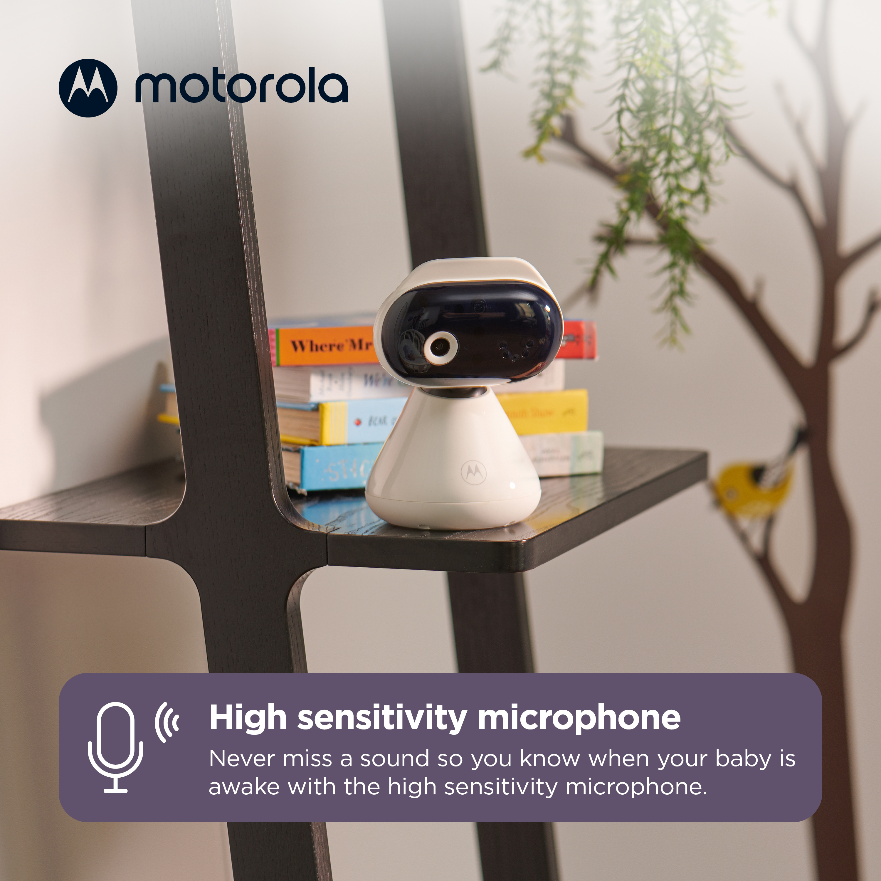 Un baby monitor bianco con testa scura è su uno scaffale accanto ai libri.