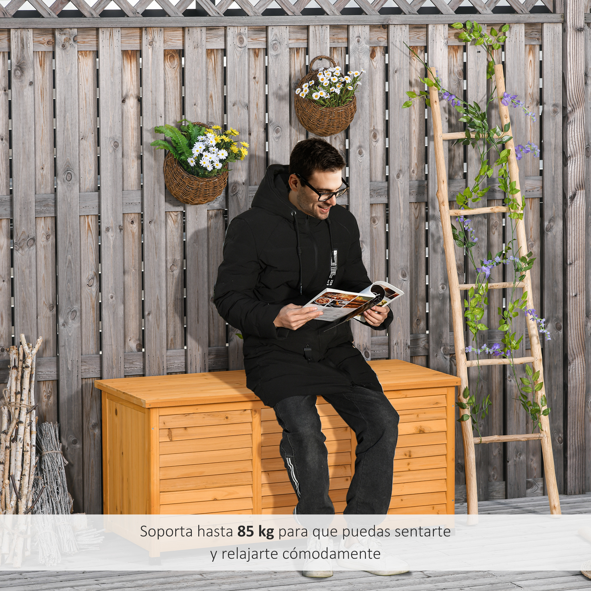 Un hombre sentado en un cofre de madera, leyendo una revista, junto a una escalera.