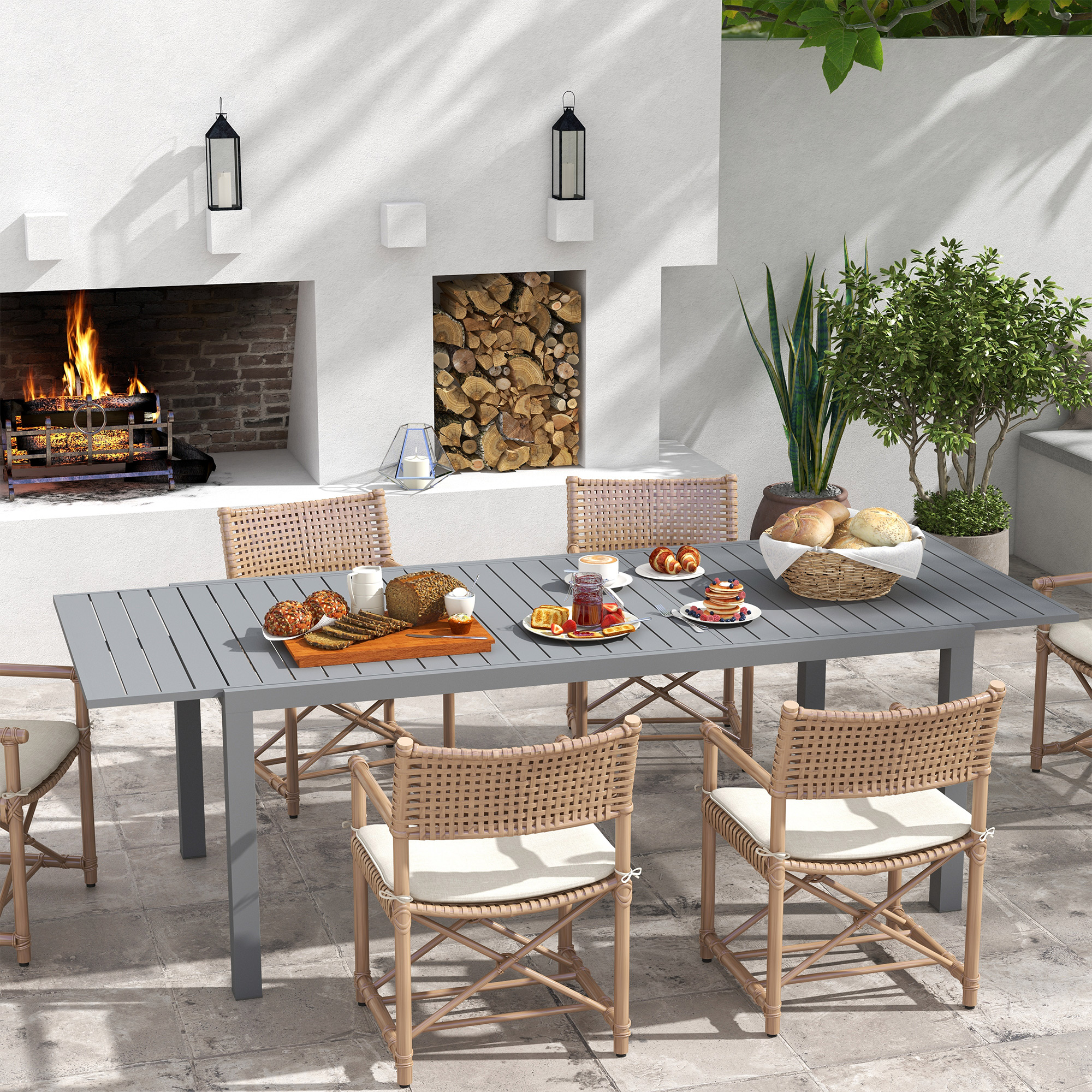 Una mesa de comedor exterior con comida y asientos frente a una chimenea.