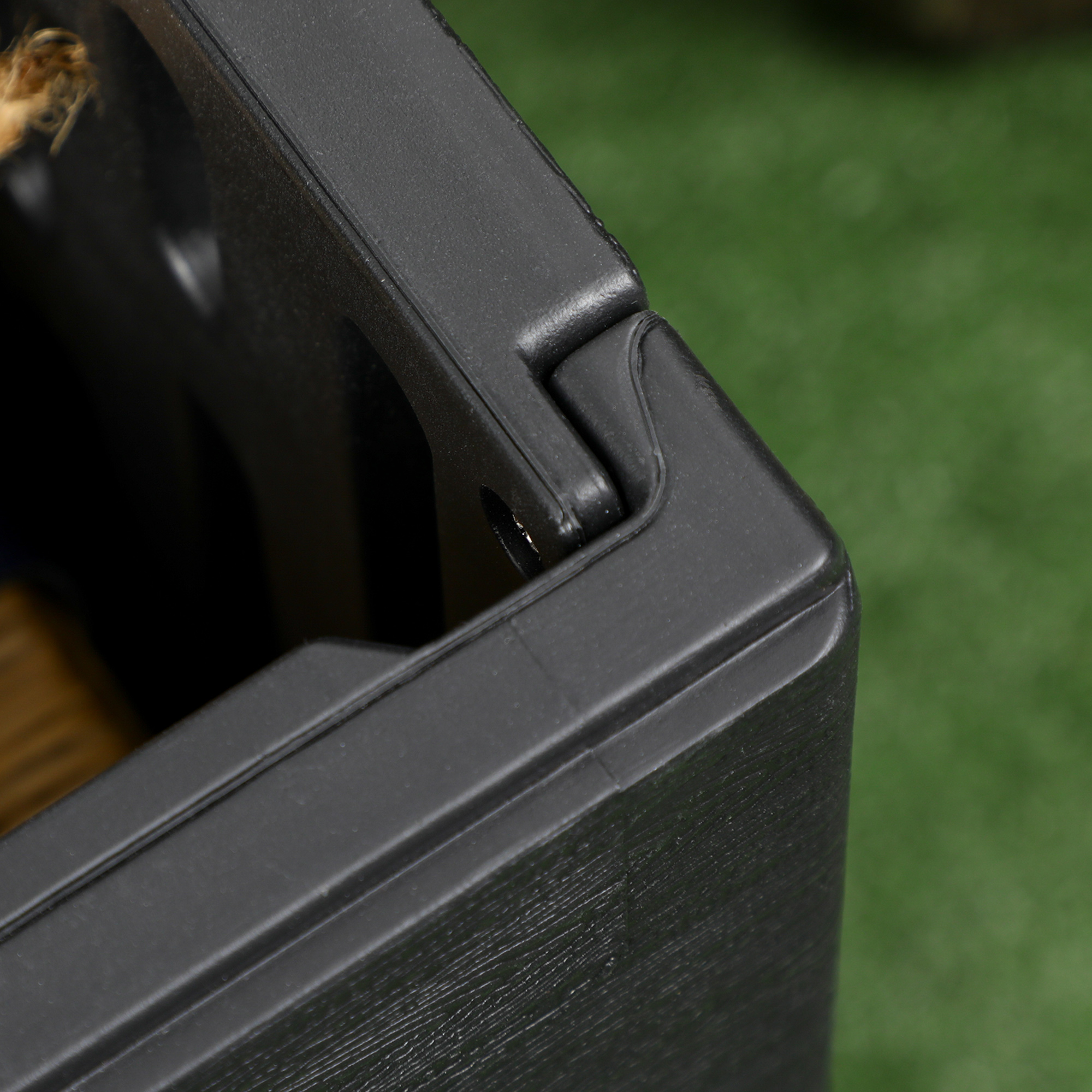 Primer plano de una caja de plástico negra con una bisagra y un trozo de cuerda.