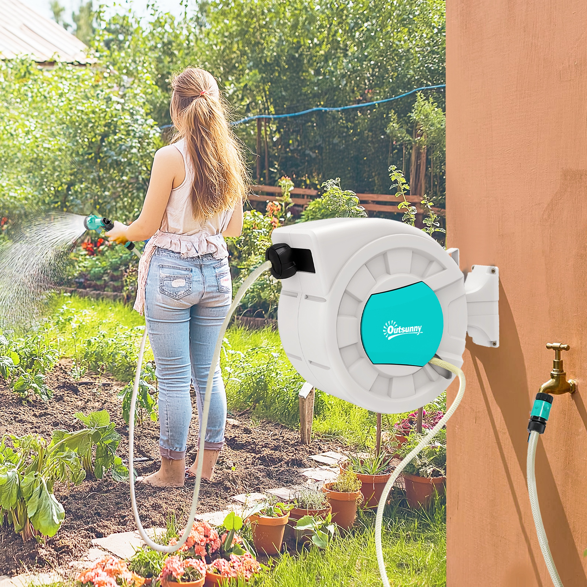 Mujer regando jardín con manguera; enrollador de manguera blanco en pared.
