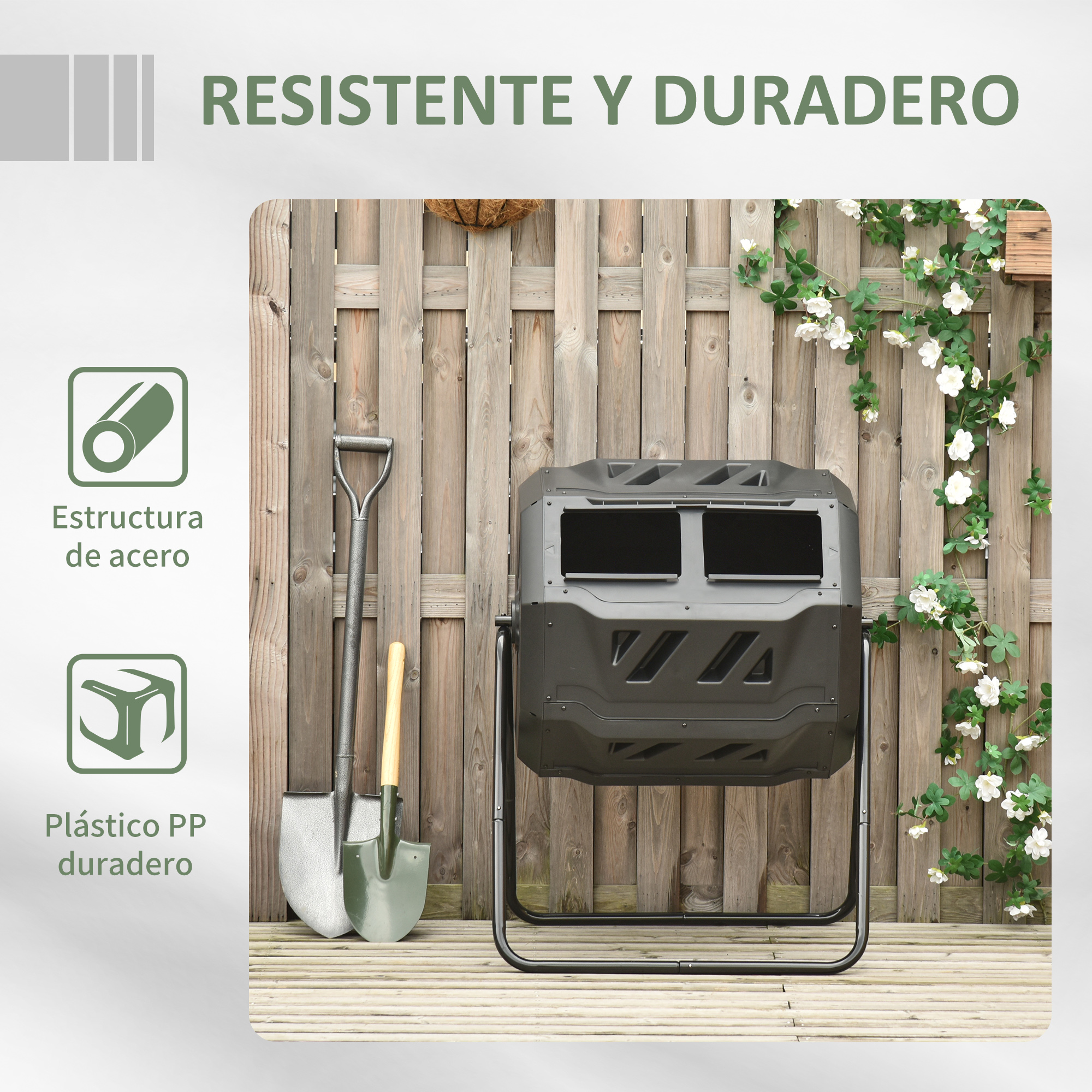 Un compostador de plástico negro junto a dos palas frente a una valla de madera.