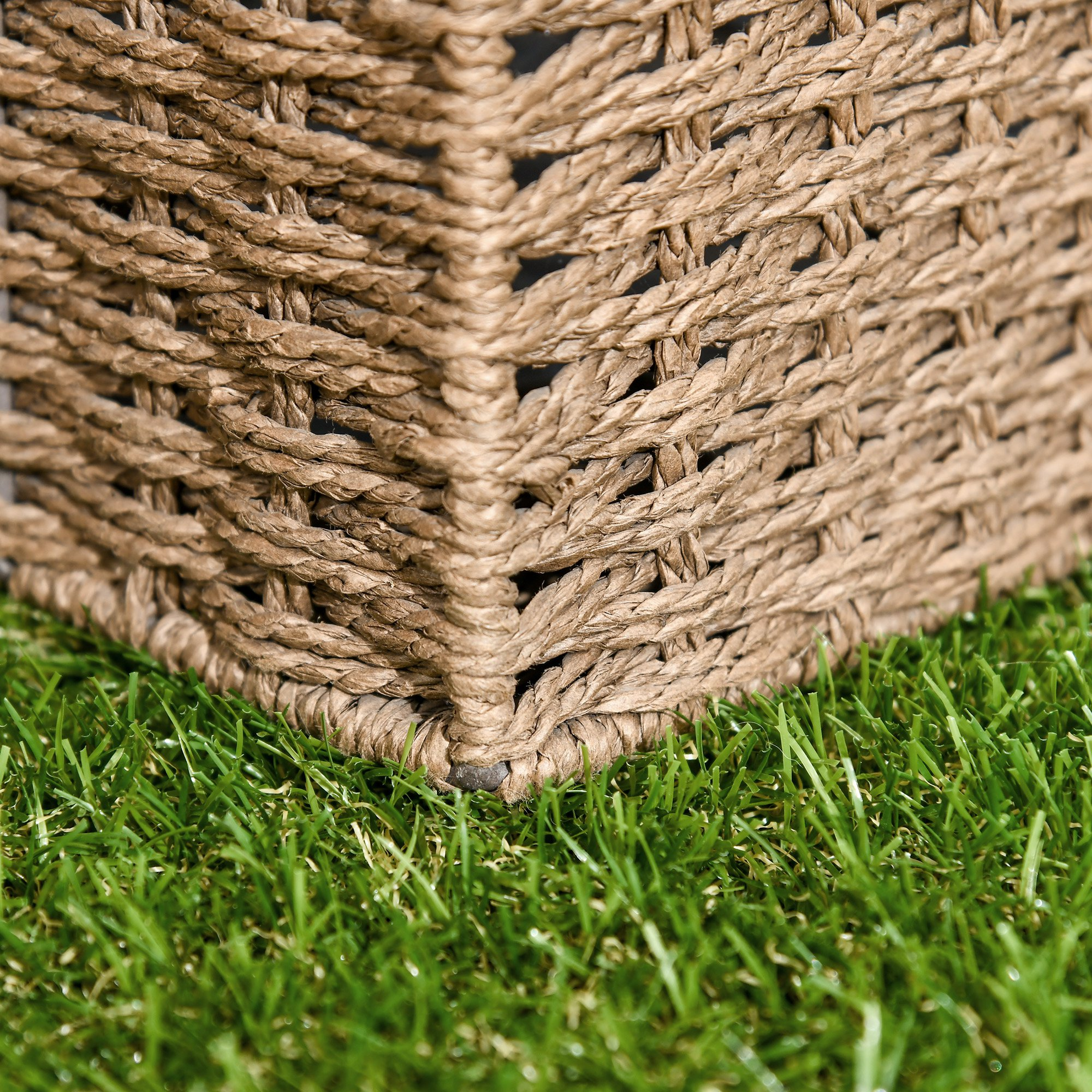 Primer plano de una cesta de cuerda marrón sobre césped artificial verde.