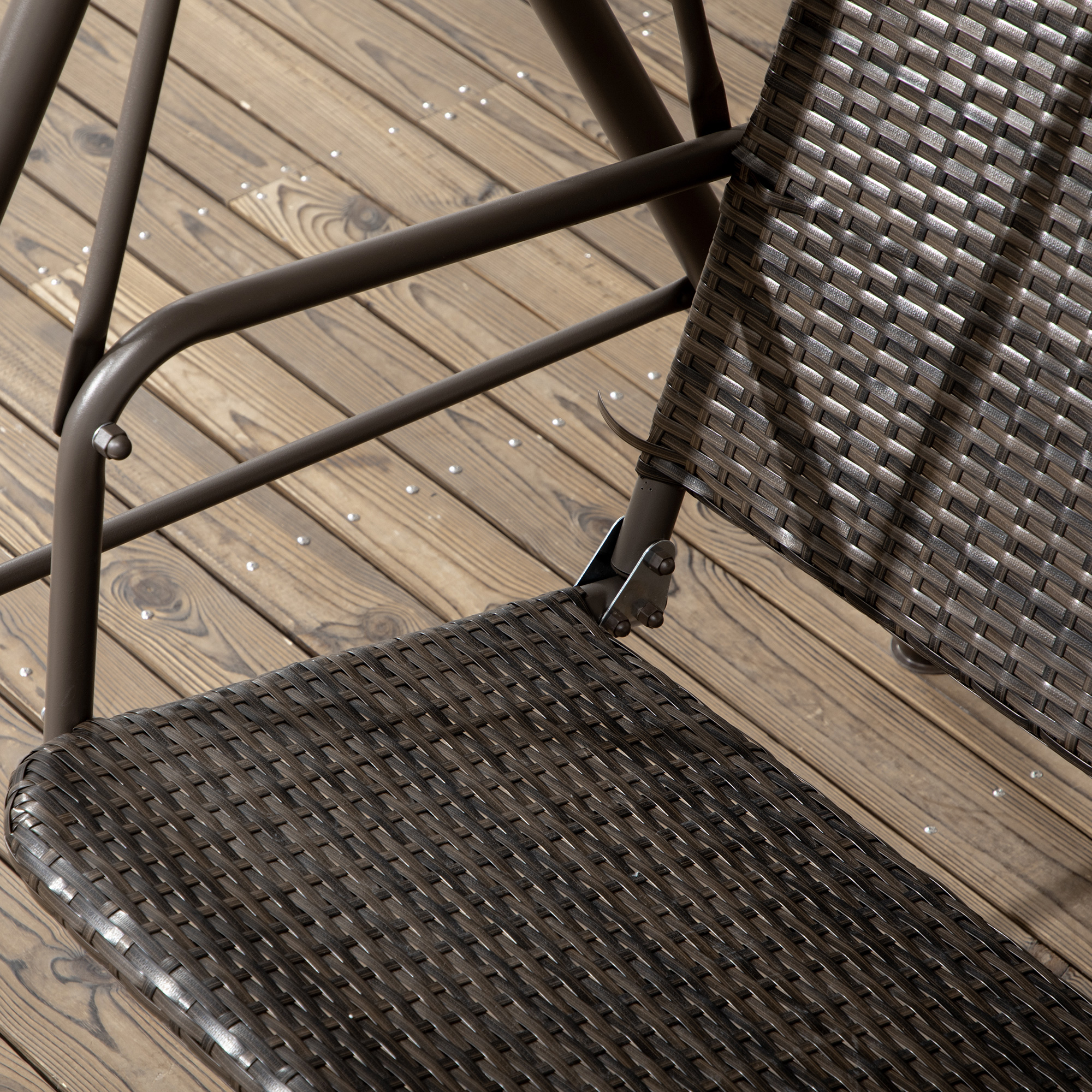 Sedia in vimini marrone su ponte di legno, primo piano della seduta e delle gambe metalliche.