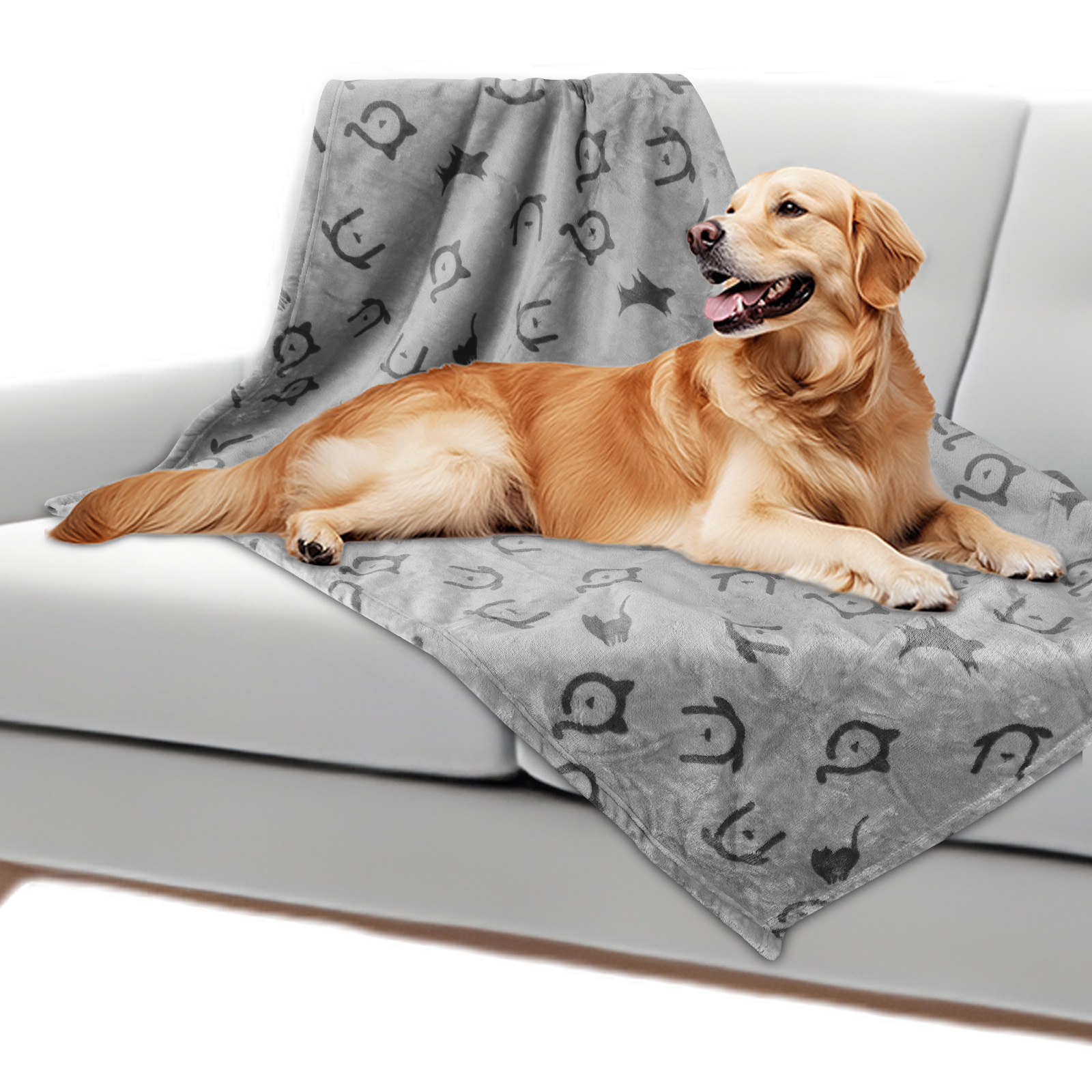 Un golden retriever yace sobre una manta gris con motivos de animales en un sofá.