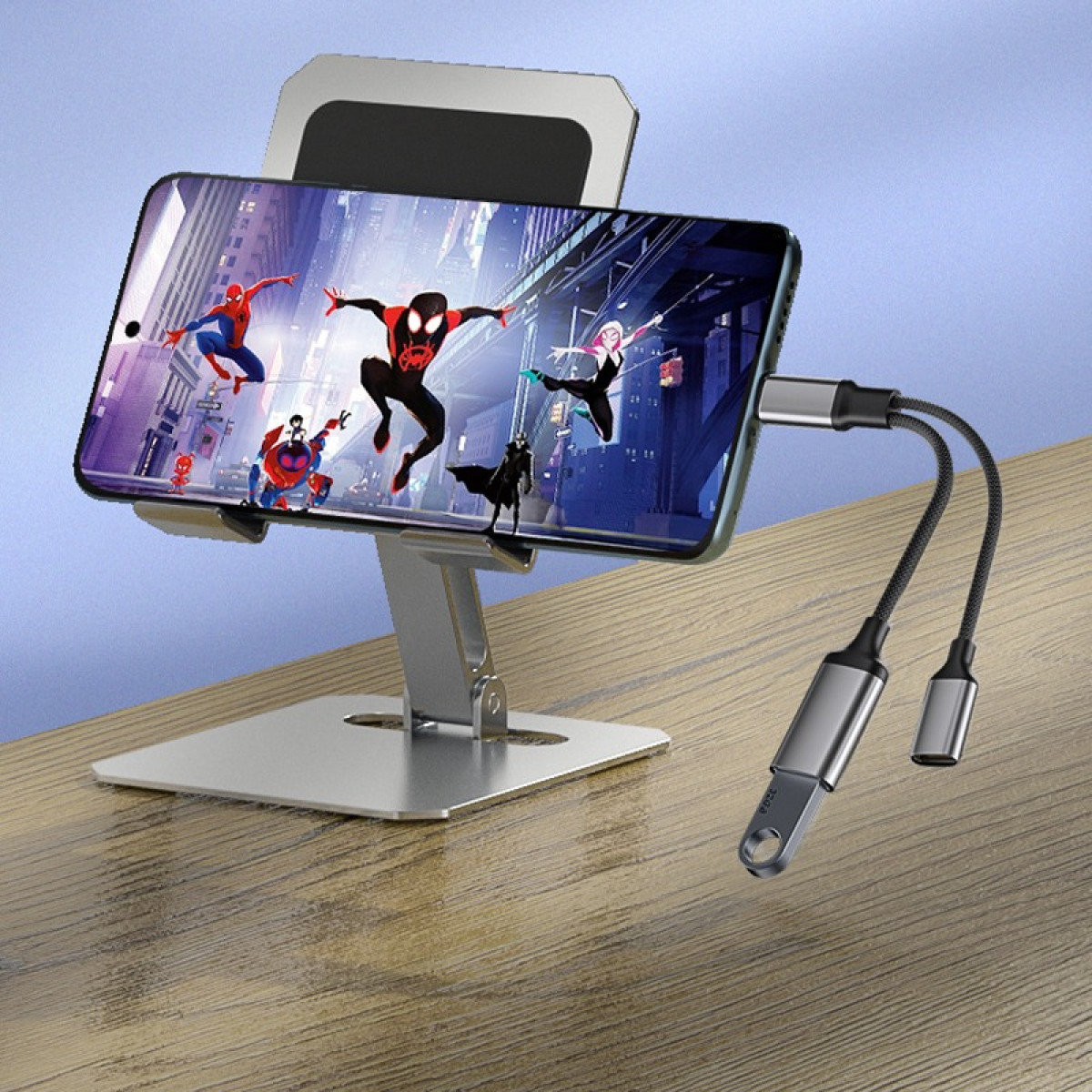 Ein Smartphone auf einem Ständer zeigt Spiderman-Charaktere. Ein Adapterkabel hängt daneben.
