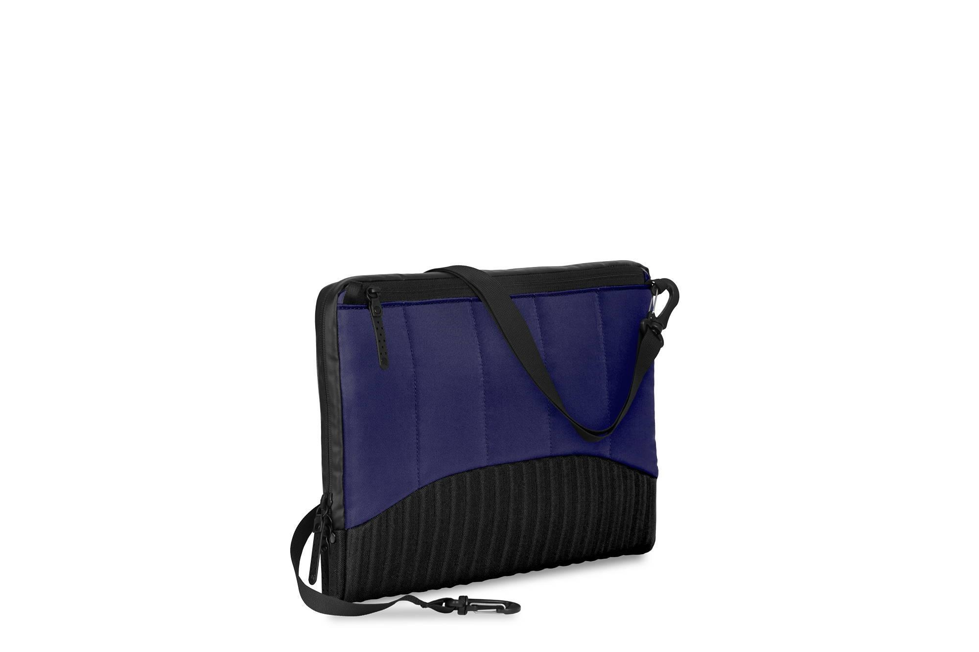 Dunkelblaue Tasche mit schwarzem Gurt und Reißverschlüssen, auf weißem Grund.