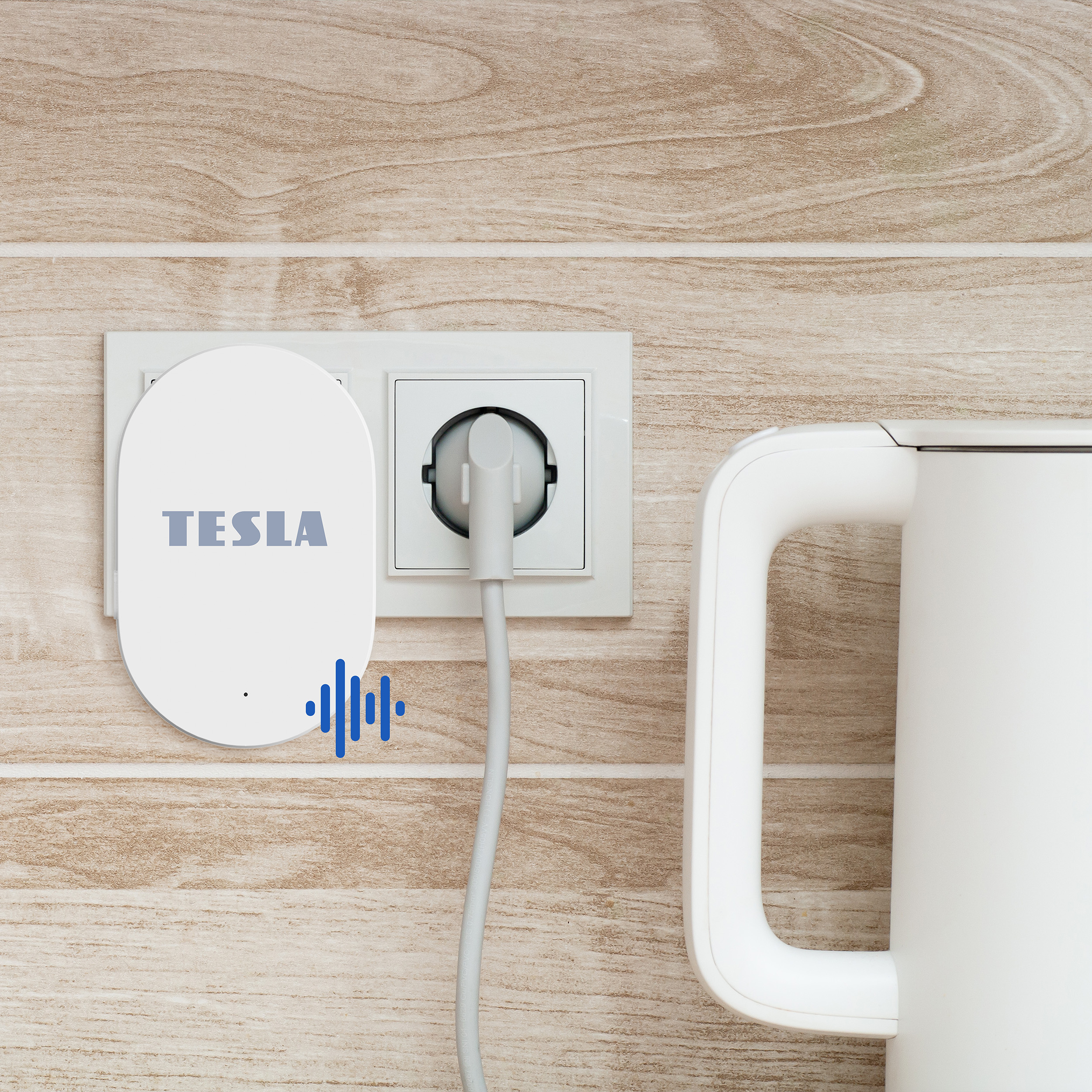 Un adattatore Tesla bianco è collegato a una presa a muro accanto a un bollitore.