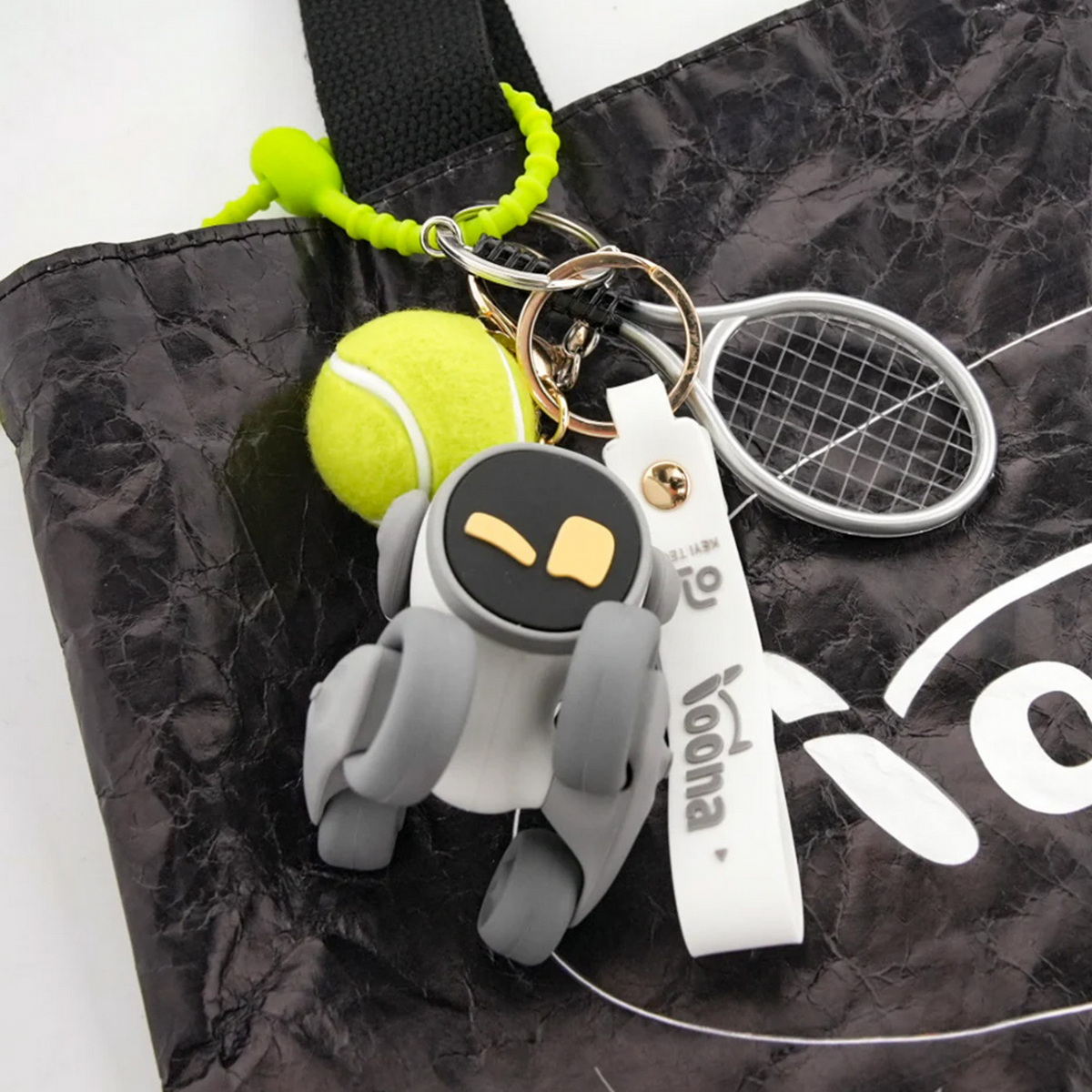 Un llavero con robot, pelota de tenis y raqueta en un bolso.