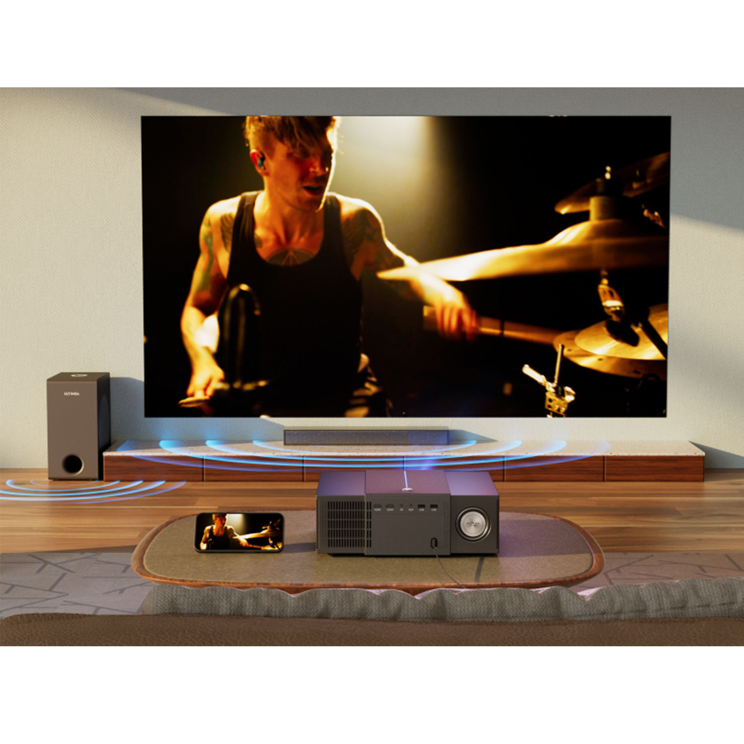 Mężczyzna gra na perkusji, wyświetlany na dużym ekranie. Projektor i smartfon na stole.