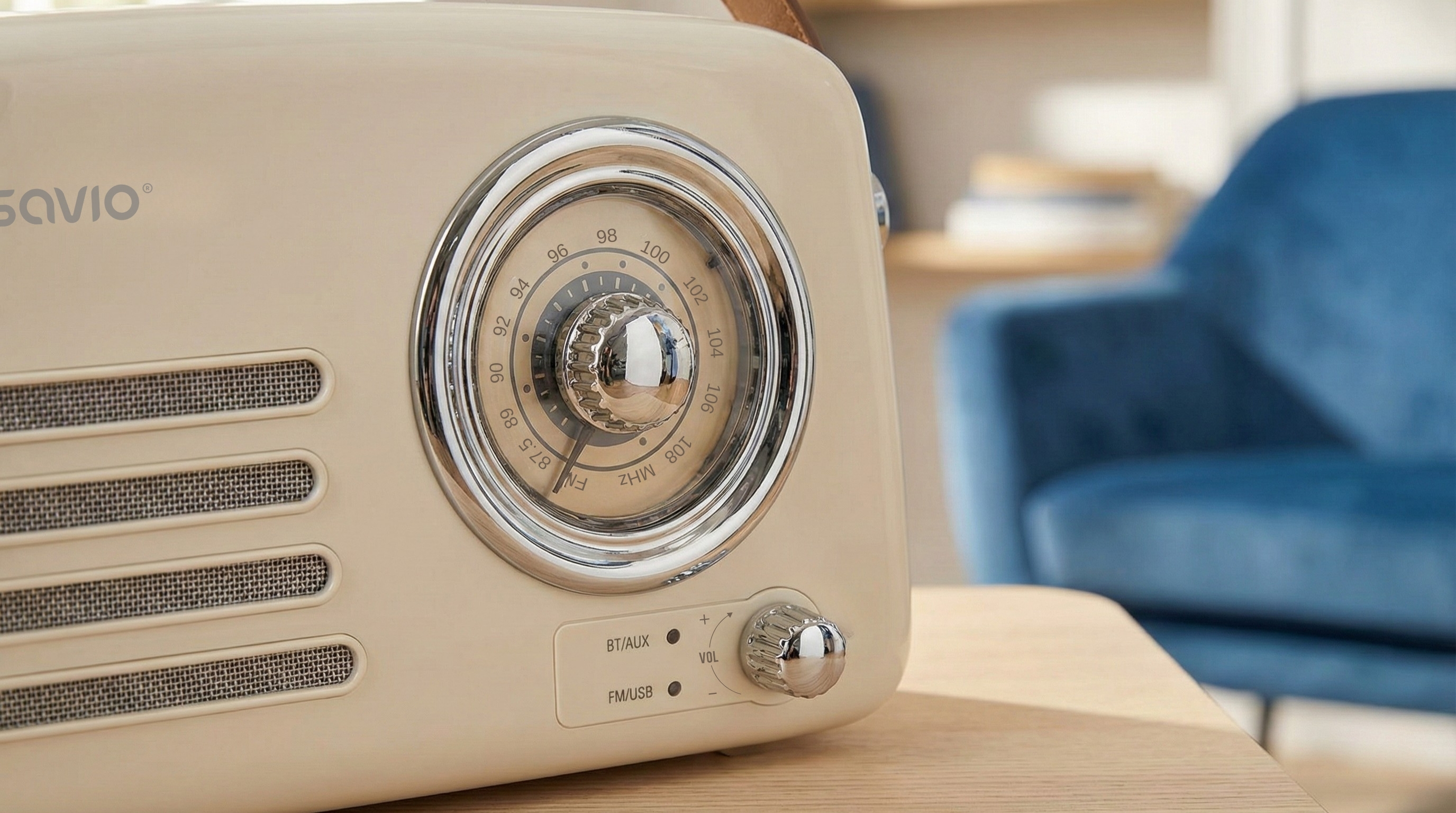Kremowe radio w stylu retro ze srebrnymi akcentami i pokrętłem stoi na drewnianym stole.
