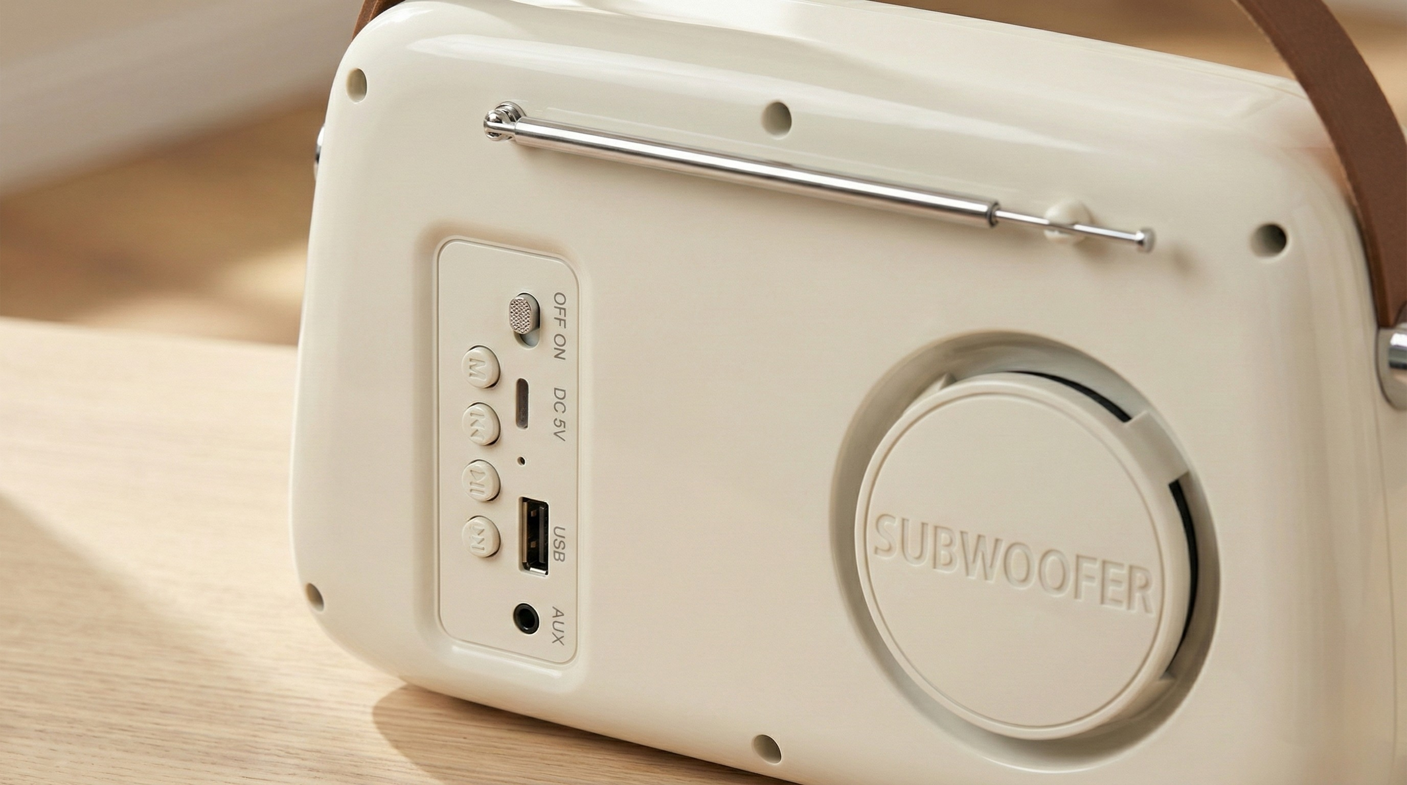 Kremowy głośnik Bluetooth ze srebrną anteną i bocznymi przyciskami.