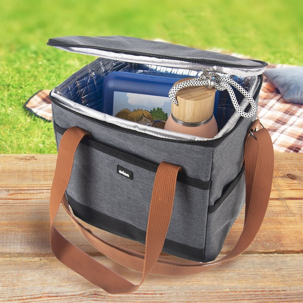 Bolsa nevera gris con asas marrones, llena de fiambrera azul y botella.
